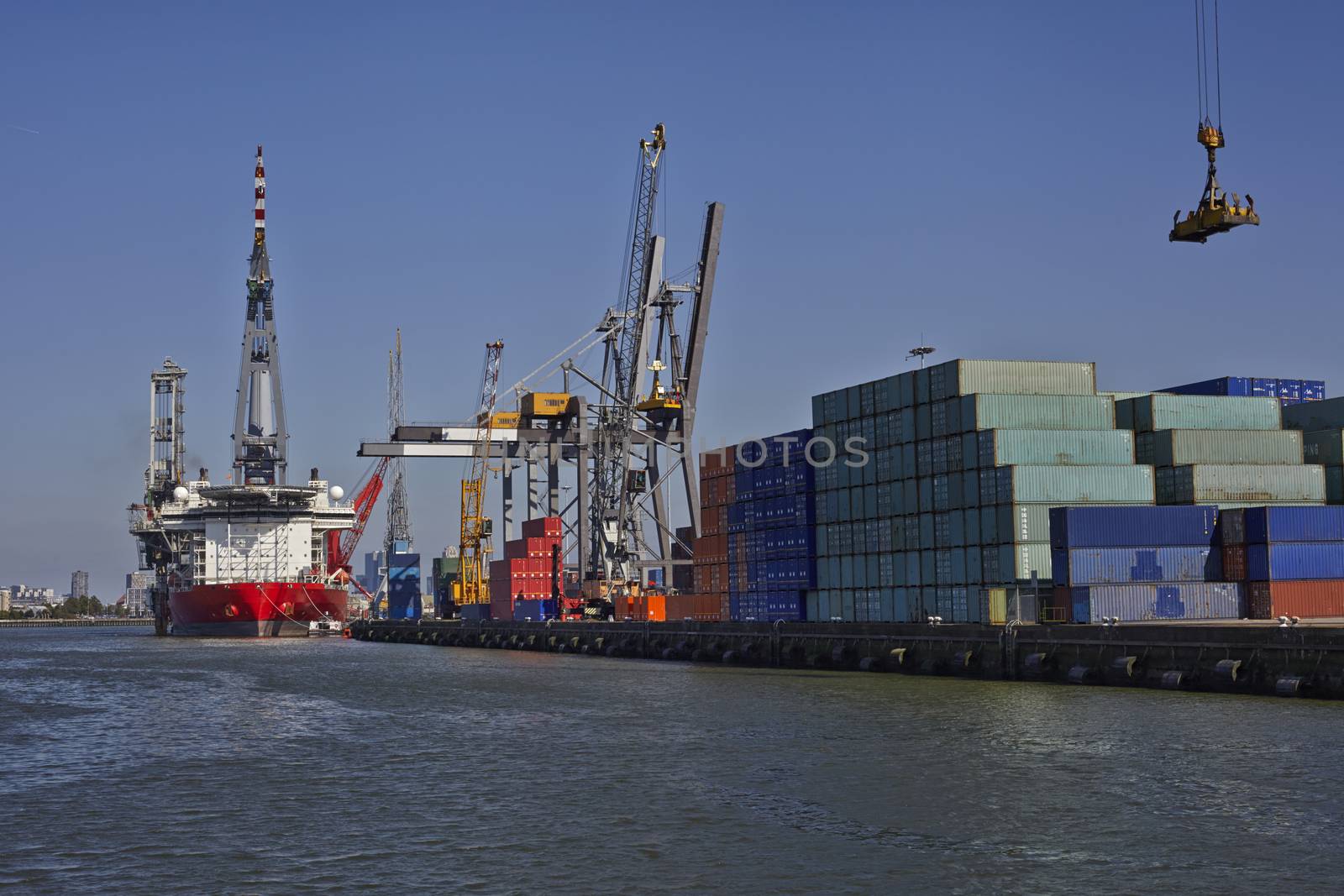 Large harbor cranes loading a large container ship in the port of Rotterdam.
