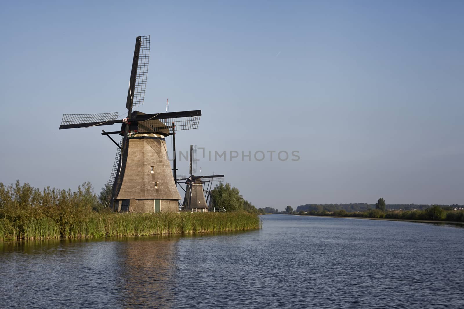 Row of traditional wind mills along blue canal in Kinderdijk, Holland
