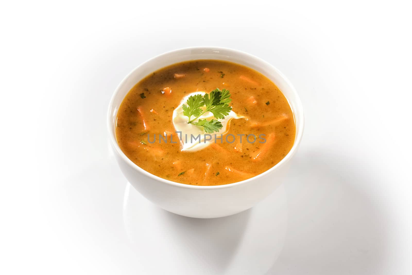 Cream Carrot Soup in a White Cup Garnished with Sour Cream