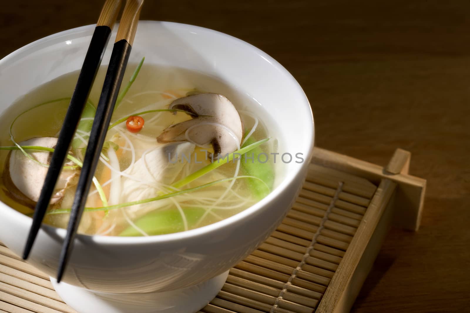 Chicken soup with vegetables in bowl with chop sticks