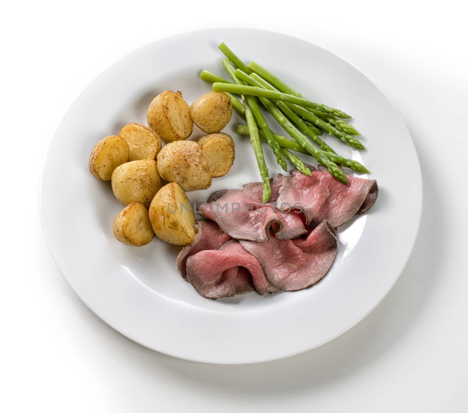 Roast with beef potatoes and asparagus on a white background by janssenkruseproductions