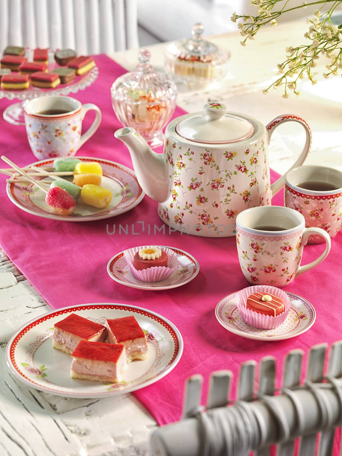 high tea on a table with a pink tablecloth by janssenkruseproductions