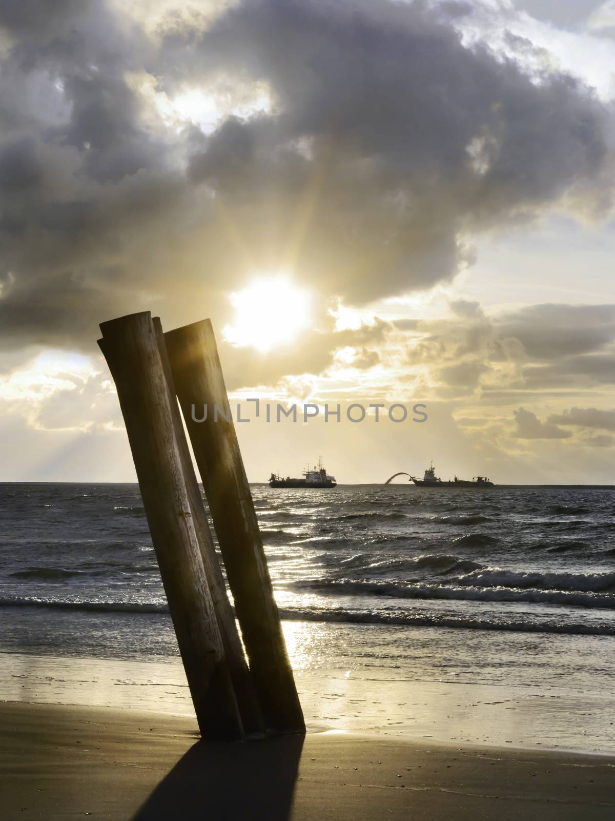 dredgers in the late afternoon sun before a beach by janssenkruseproductions