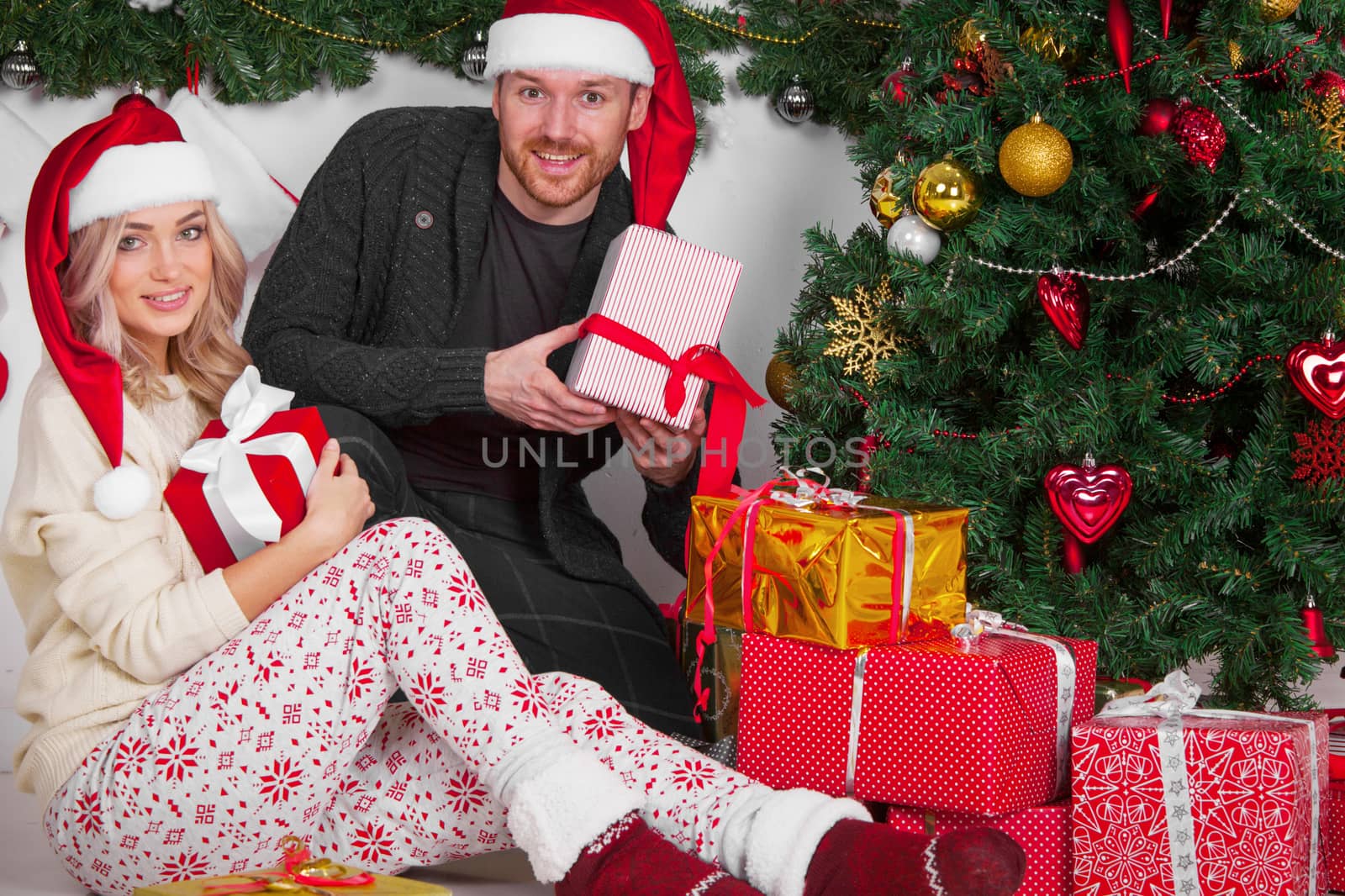 Happy young people with gifts near Christmas tree