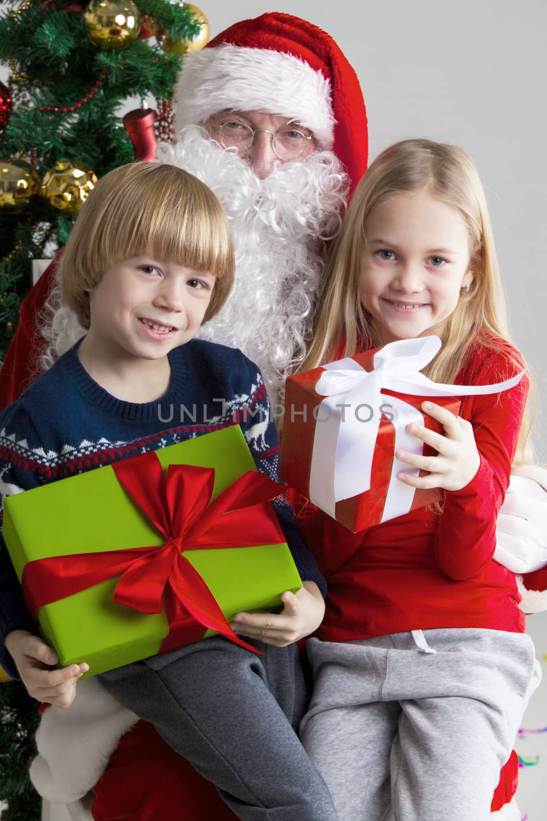 Santa Claus and children with christmas gifts near christmas tree