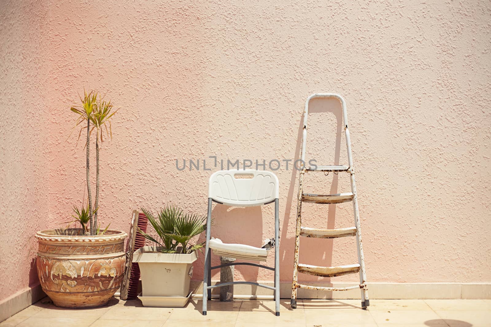 Mainstream fashion photo. Objects standing in a row stepladder chair pot on wall background