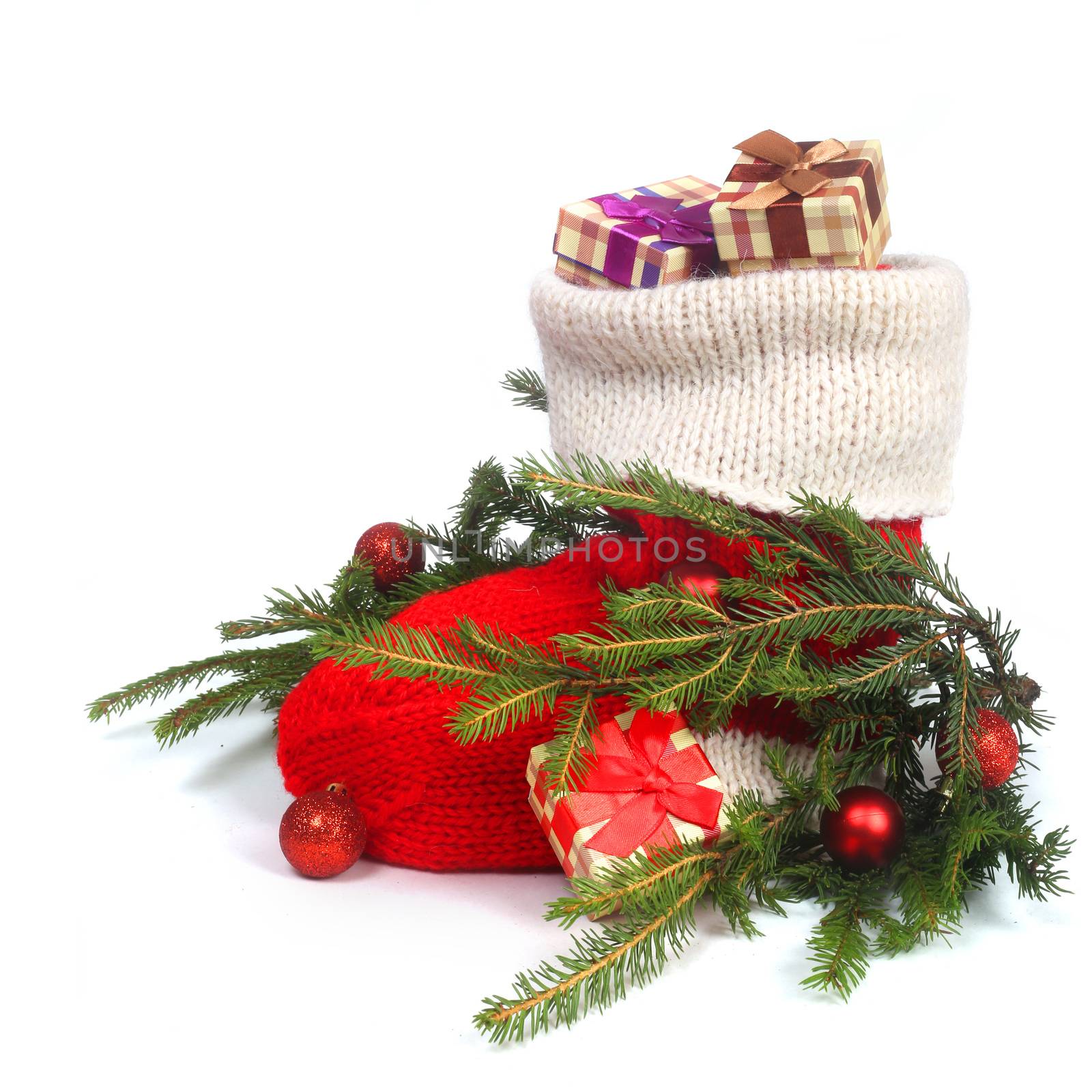 Red Christmas sock with gifts and decorated fir branch isolated on white background