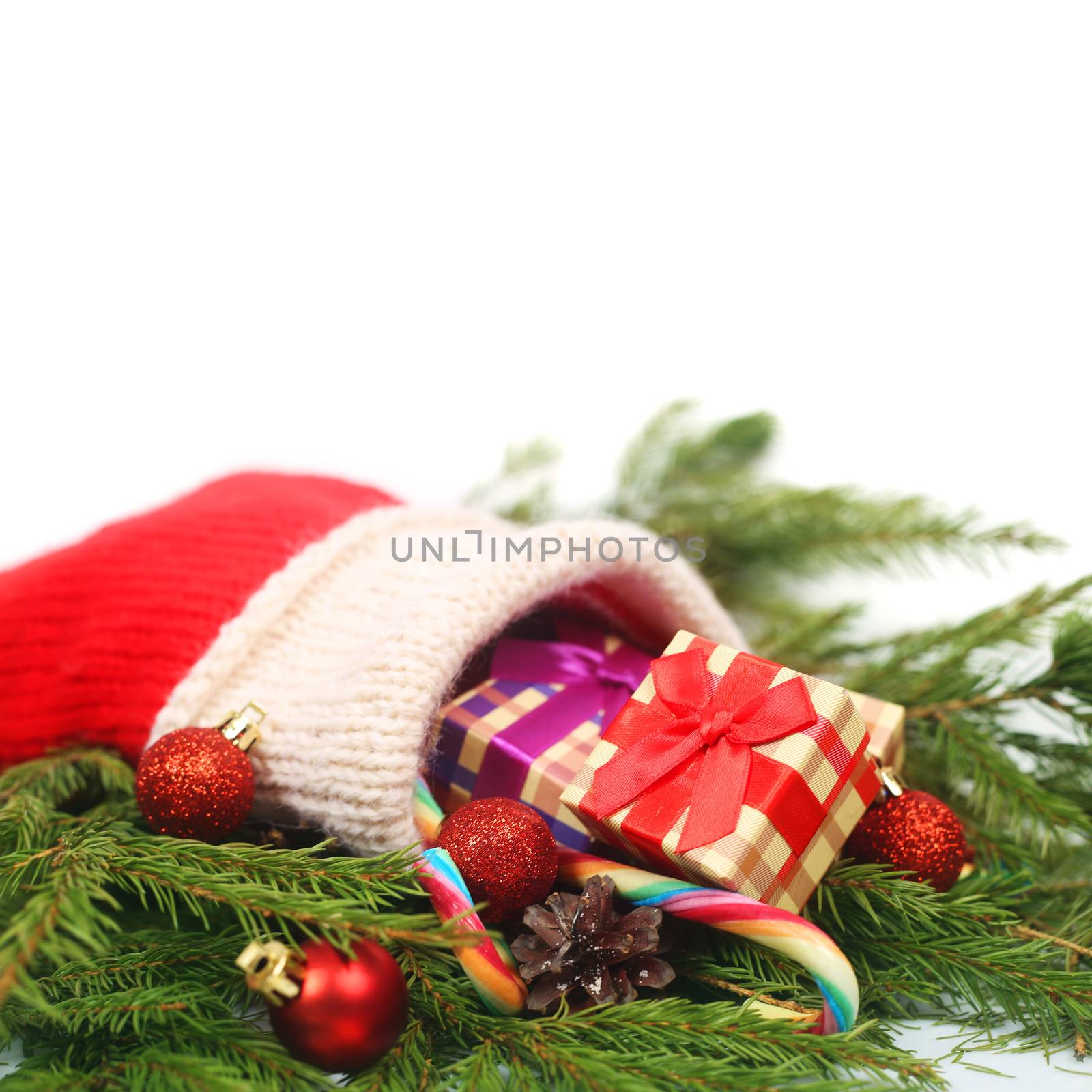 Red Christmas sock with gifts and fir branch isolated on white background