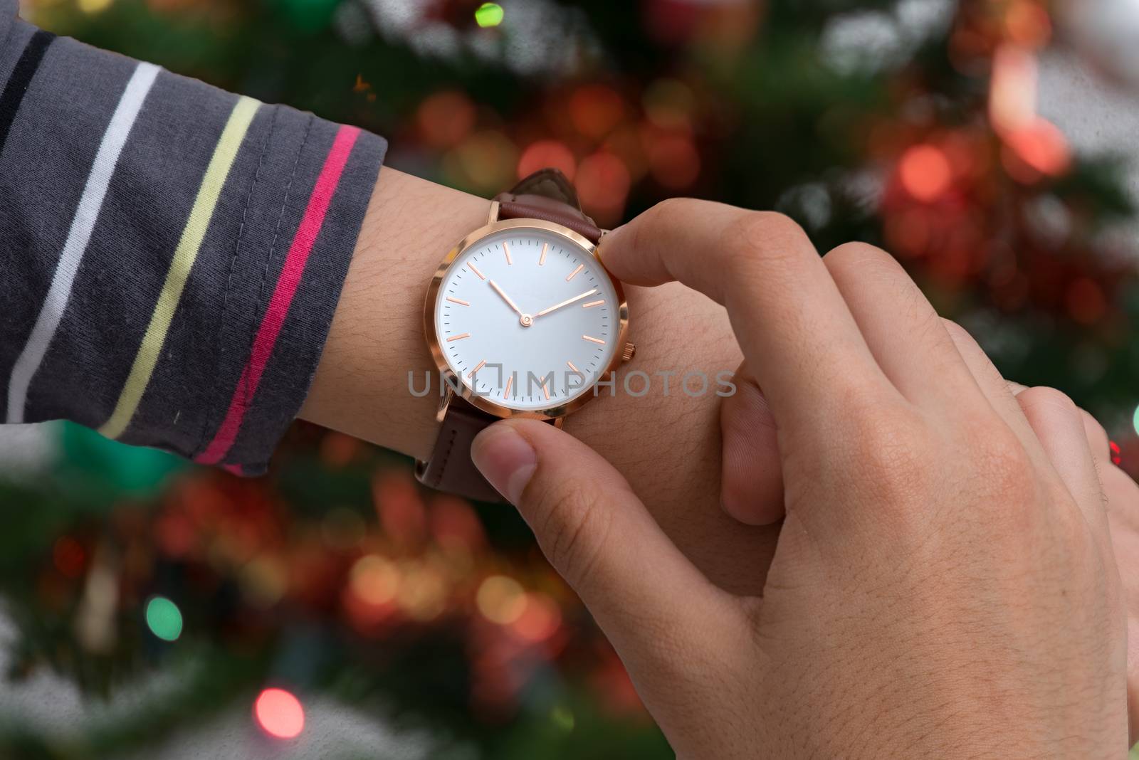 Wrist watch on girl's hand in christmas time in front of a Christmas tree in background