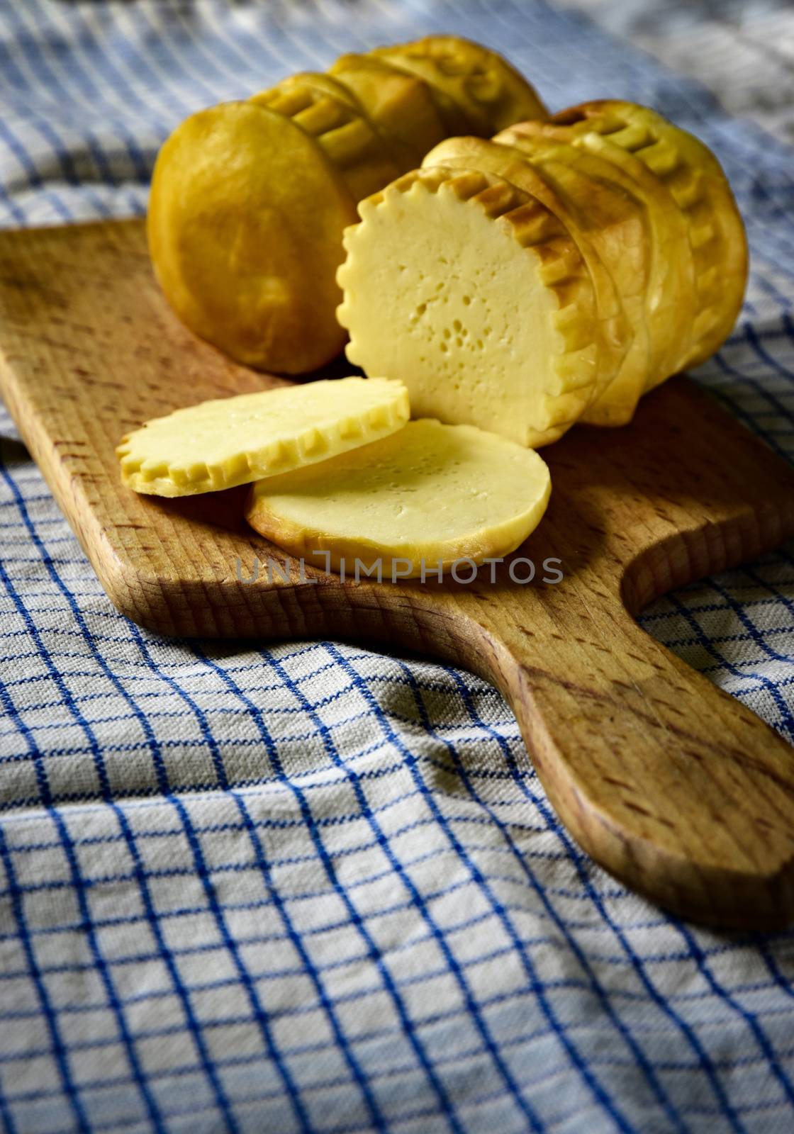 traditional smoked cheese on a wooden plate by Ahojdoma