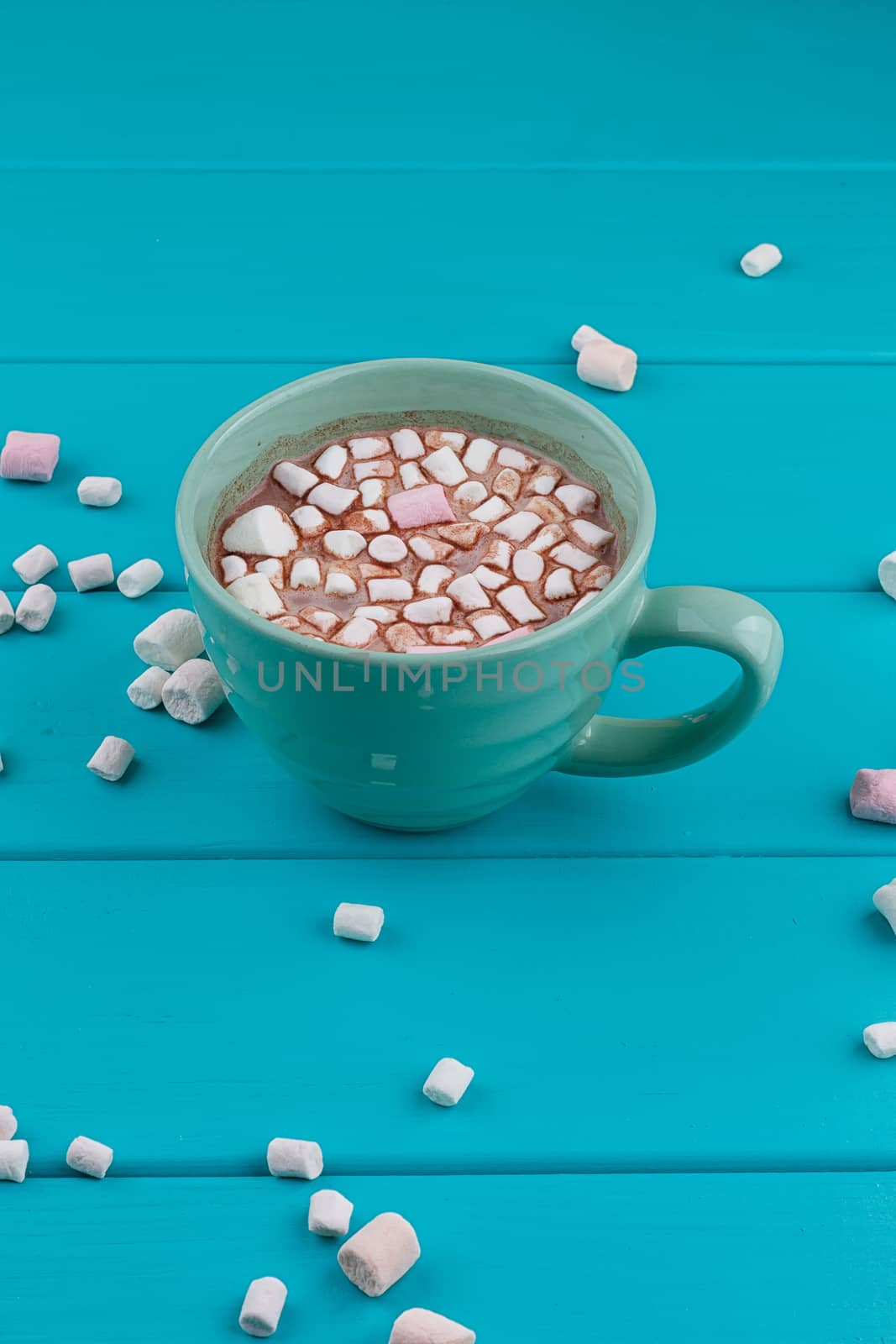 Blue cup of hot cocoa with marshmallows on blue wooden background