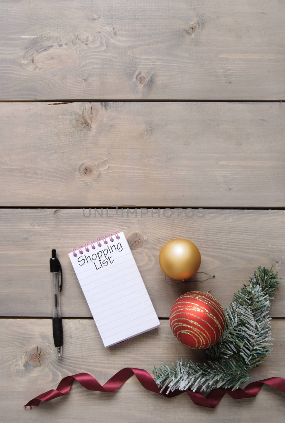 Notepad with Christmas shopping list over a wooden background