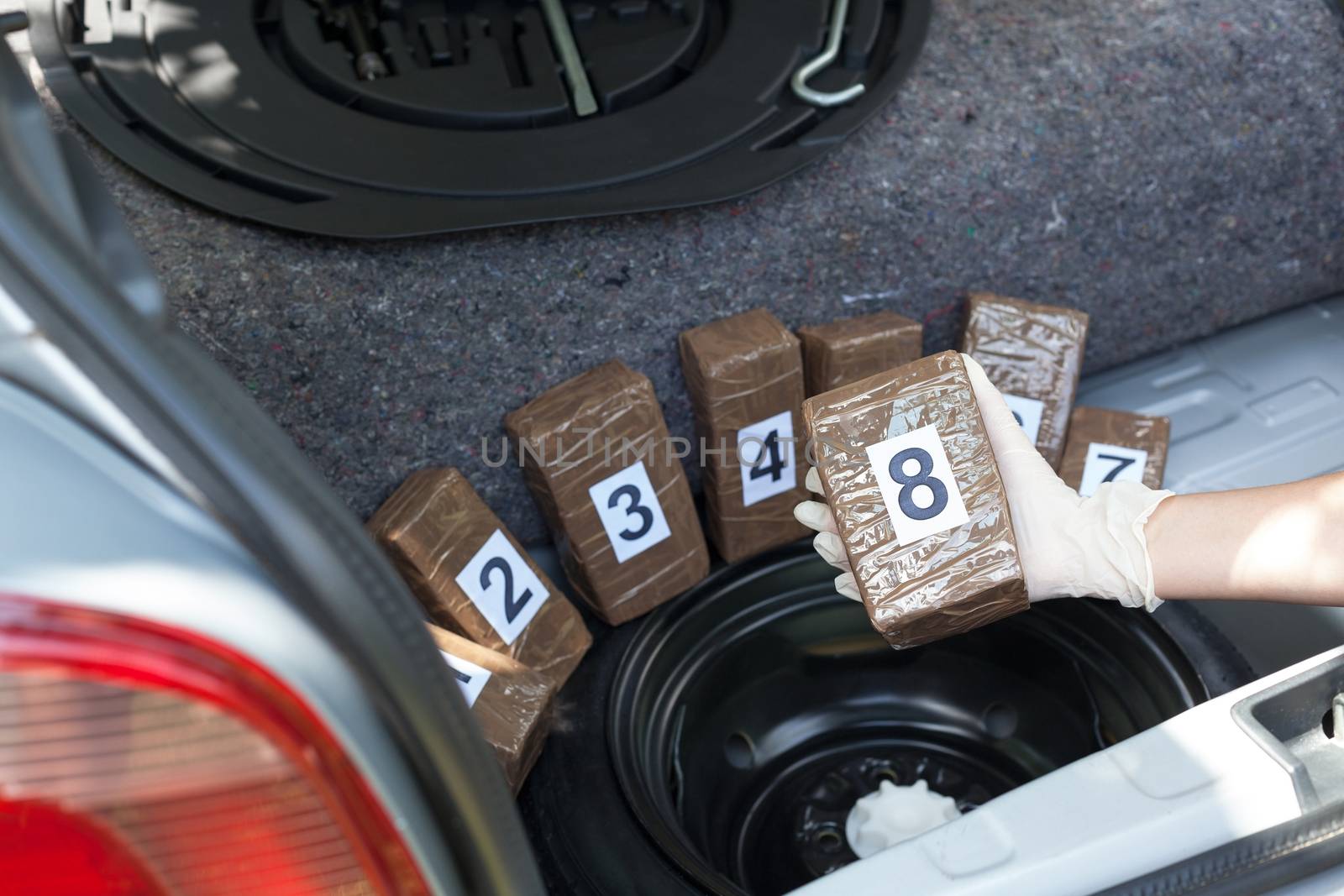Police officer holding drug package discovered in the trunk of a car by wellphoto
