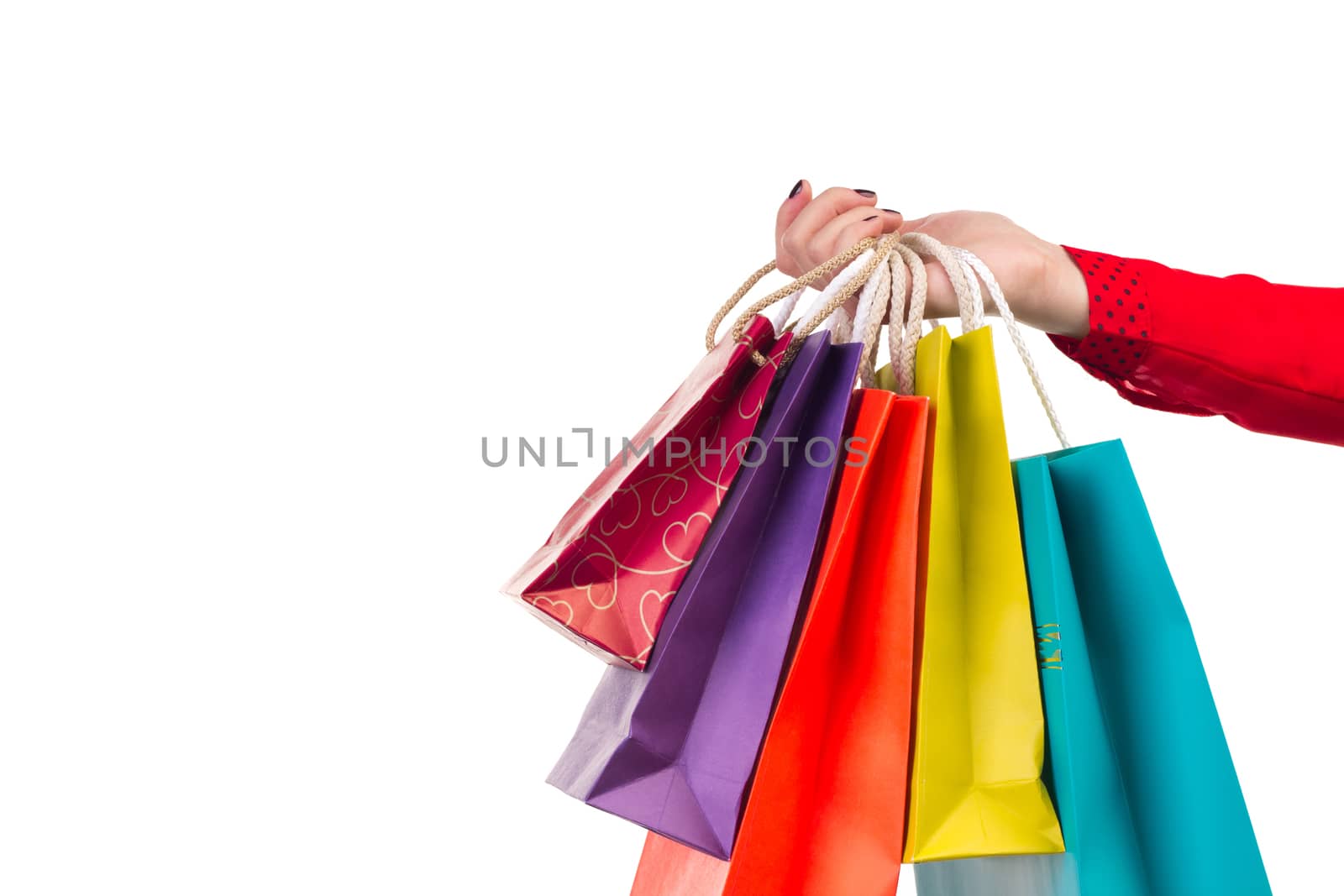 Colourful and bright shopping paper packages hanging on female red-sleeved arm