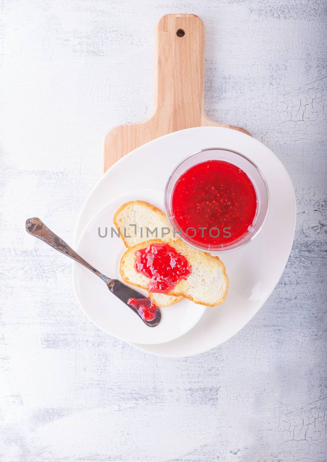 Raspberry jam in bowl with toast and knife