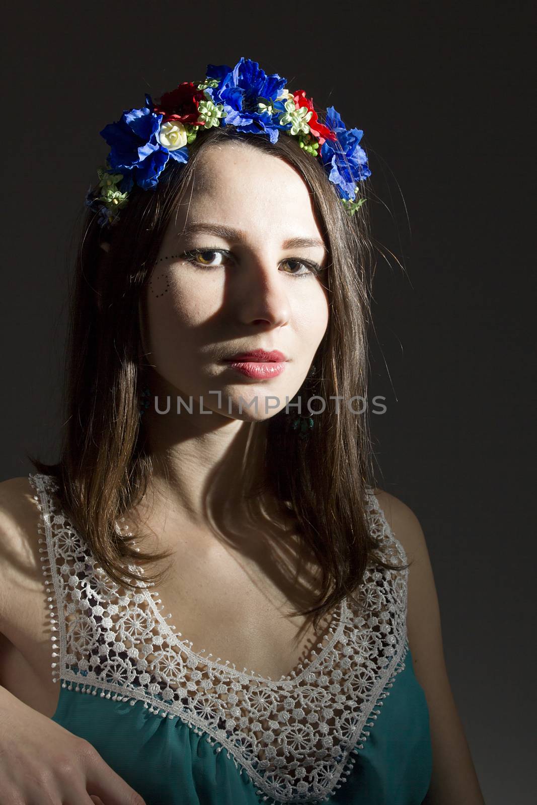 Portrait of a girl in a wreath of flowers on a dark background