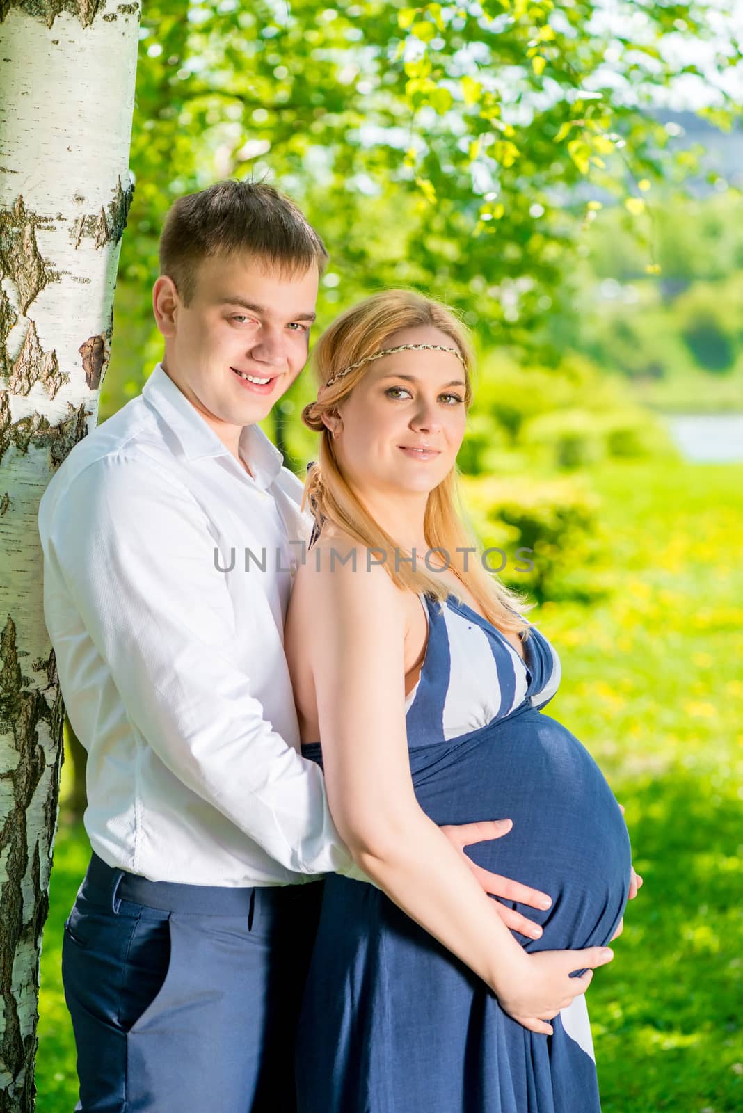 man tenderly embracing his pregnant wife, shot in the park