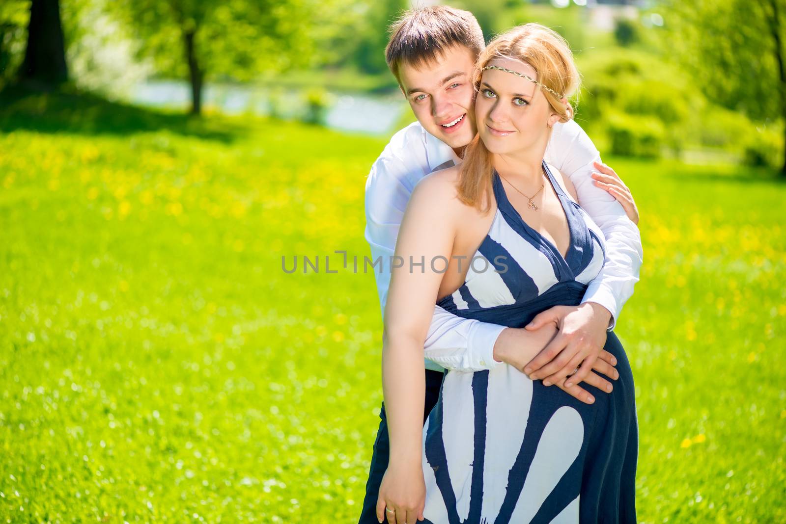 Pregnant woman and her husband walking in the summer park