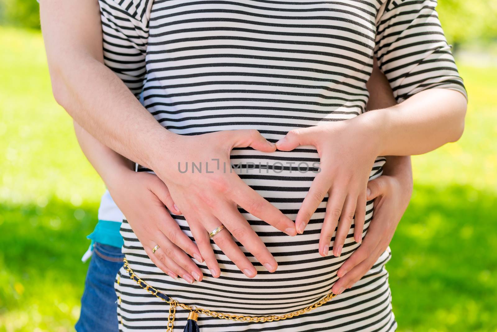 pregnant belly and hands in a heart shape on the belly expectant mother