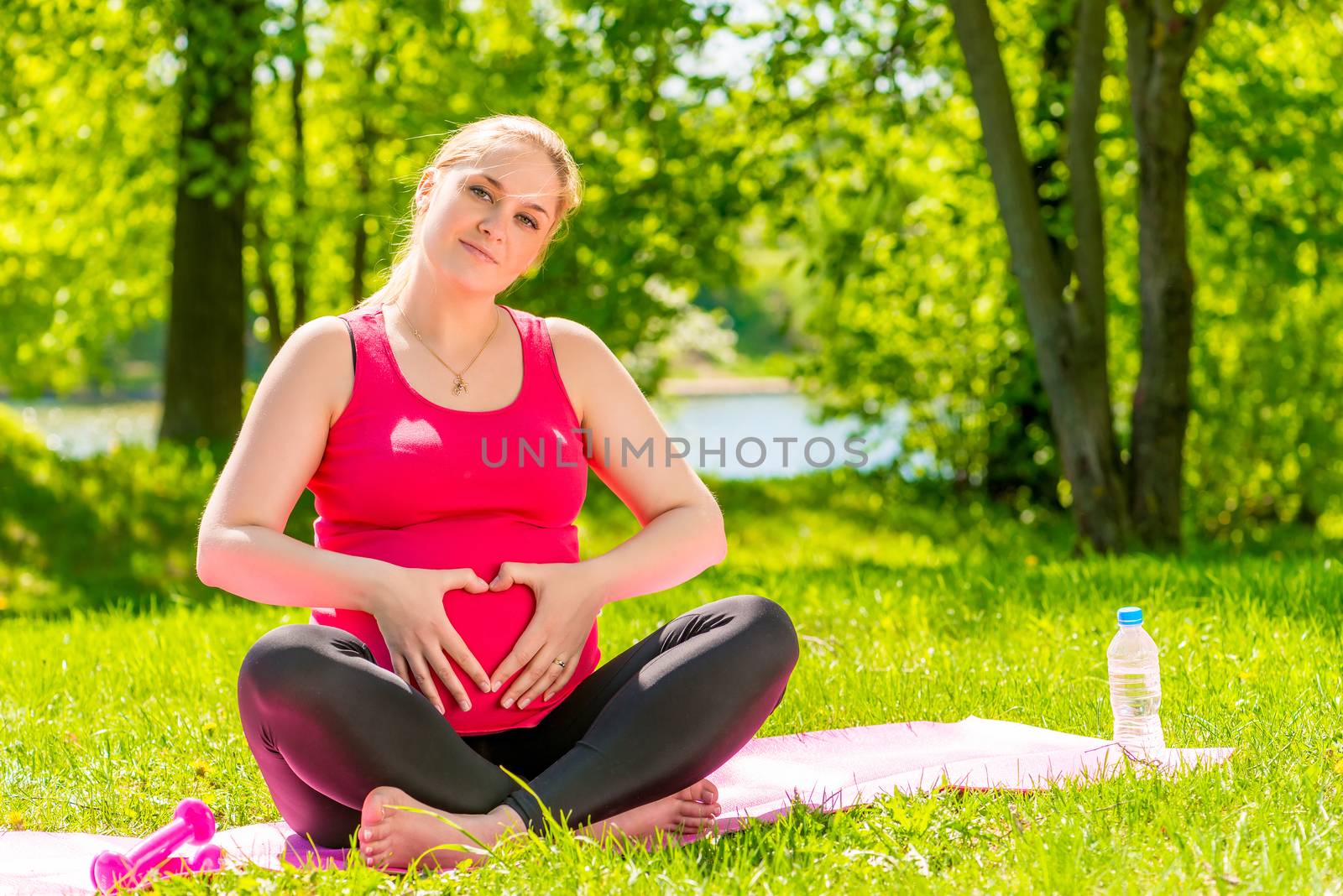 beautiful pregnant woman showing heart symbol hands near the abdomen