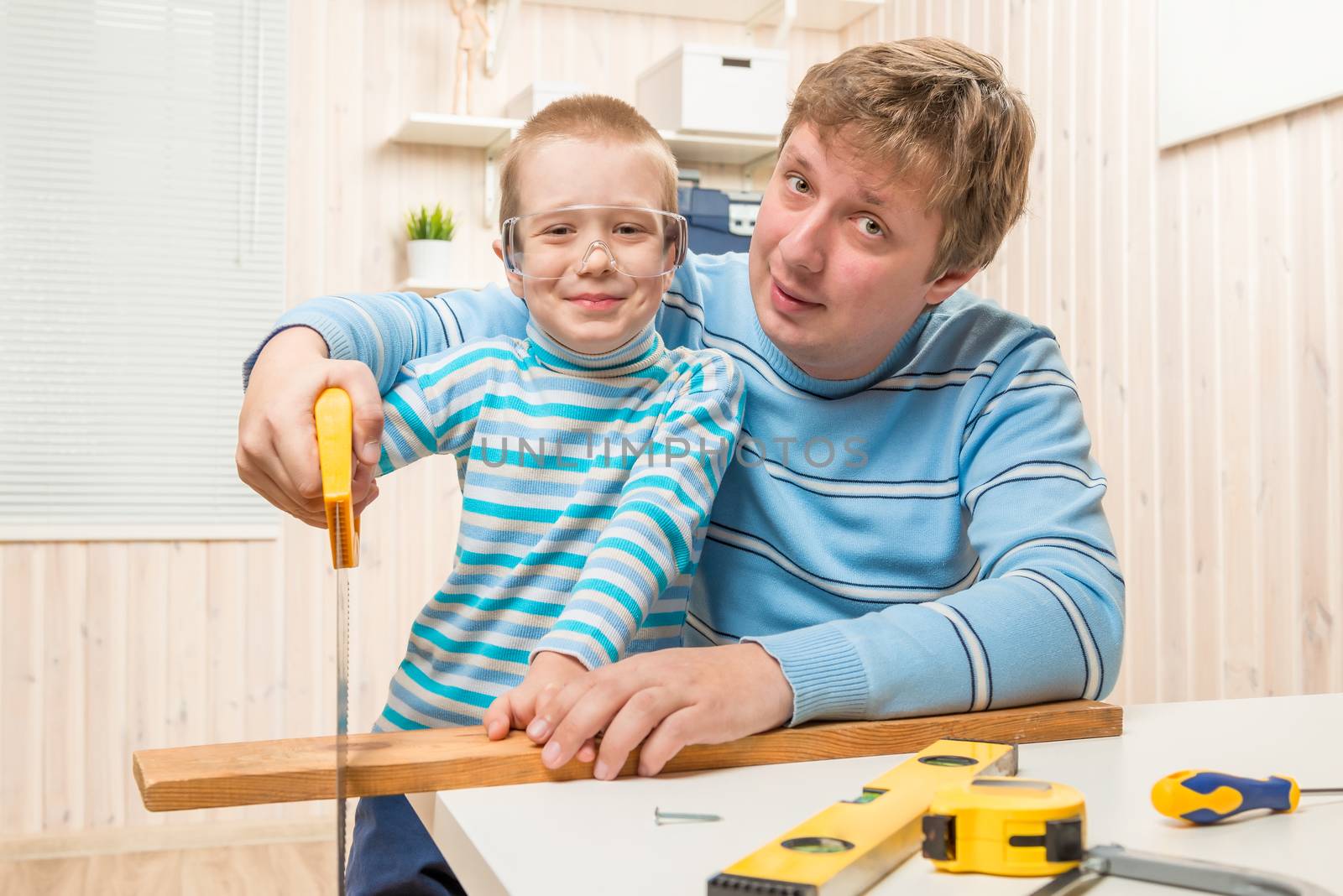 father teaches his son to cut the wooden plank saw