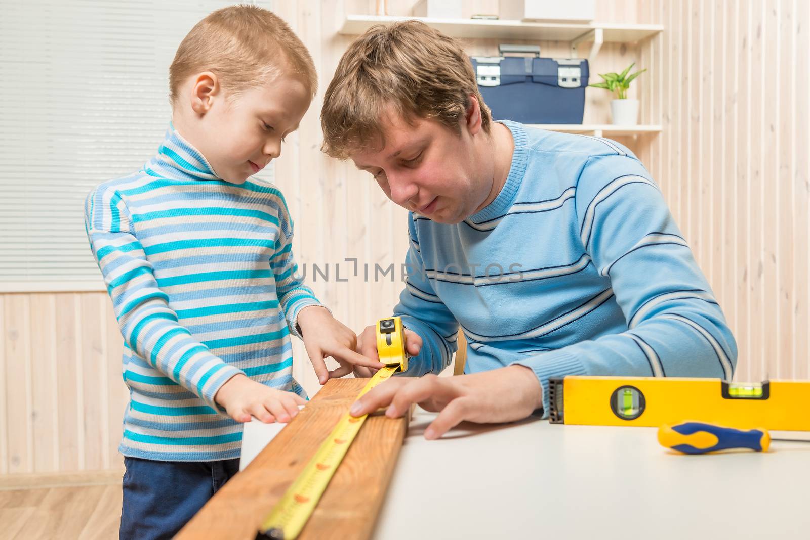 boy helps his father in the work of the carpenter