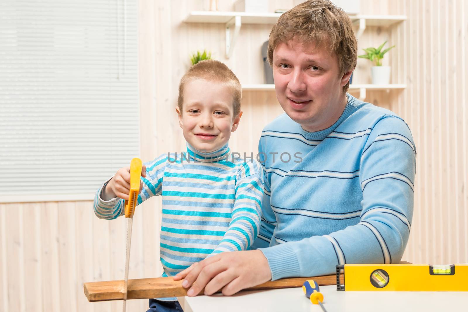 Son with his father working with tools and boards in the garage