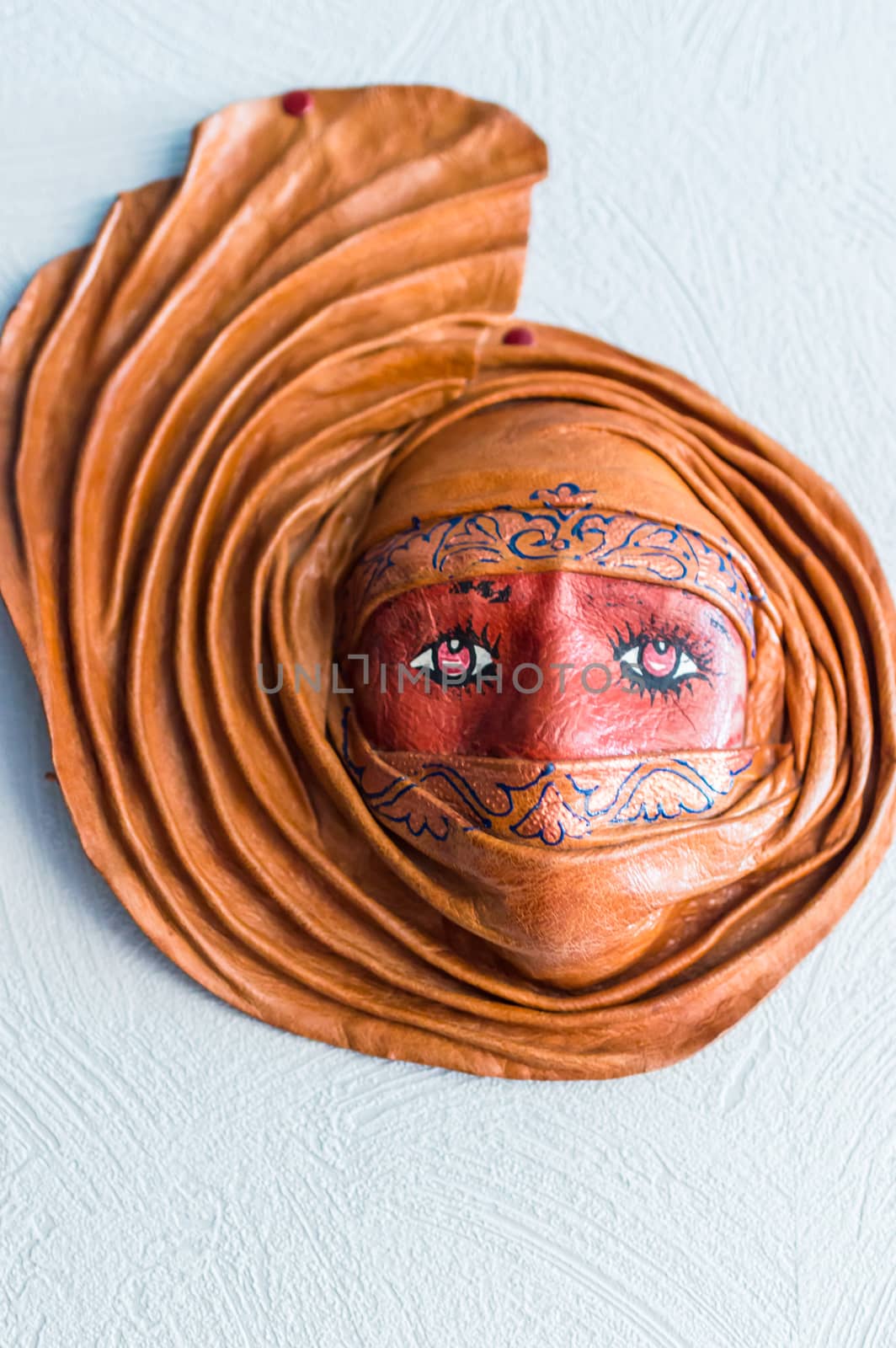 fashioned from clay mask hanging on a white wall