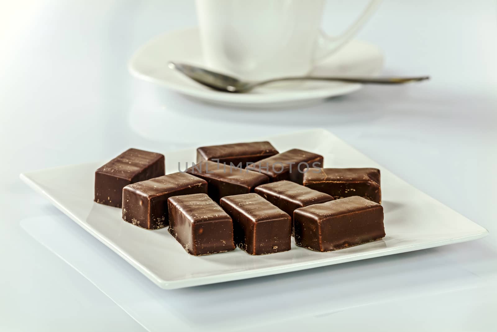 Chocolates on a plate next to a cup of coffee in the office