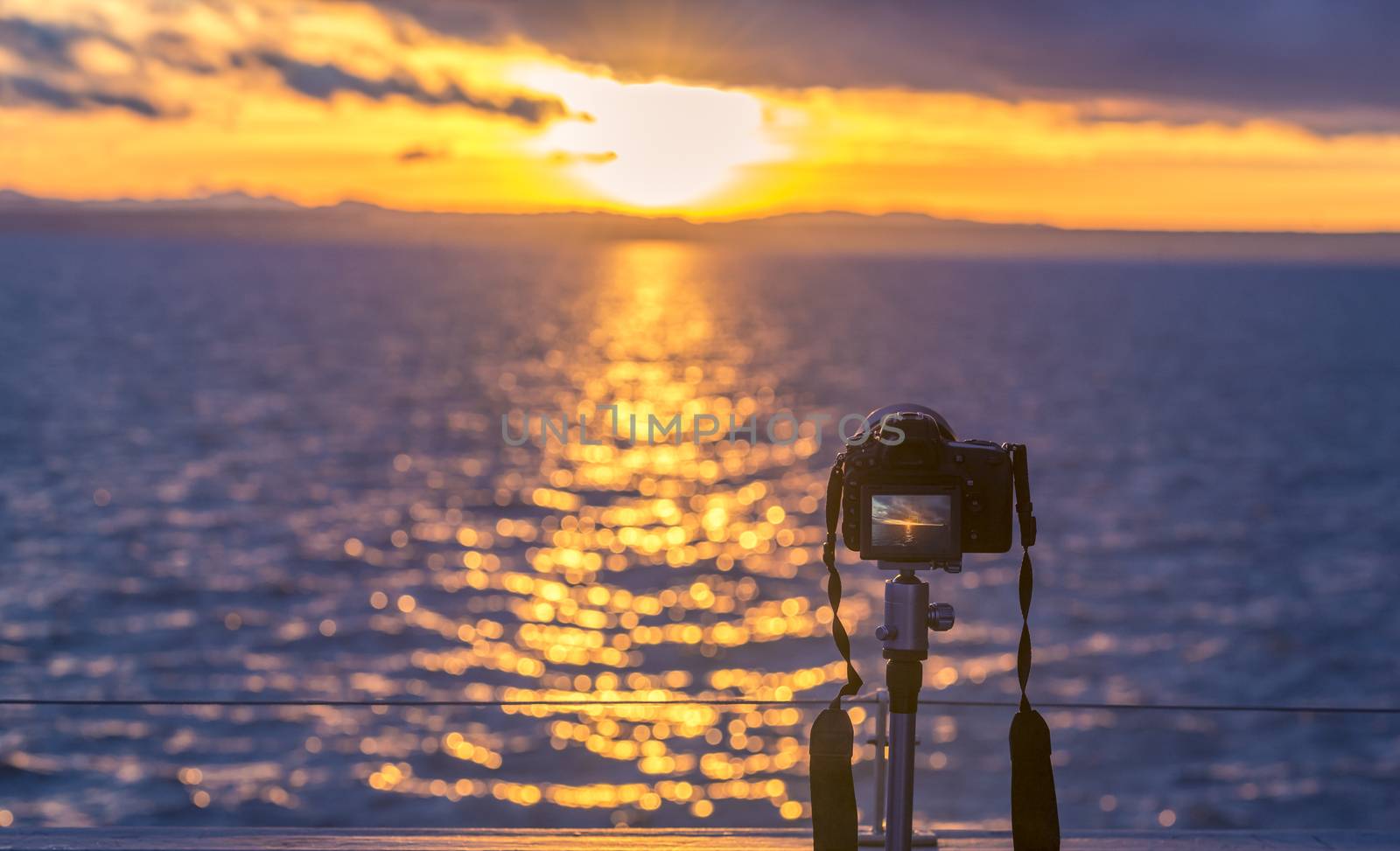 Sunset over water and a DSLR camera  by YesPhotographers