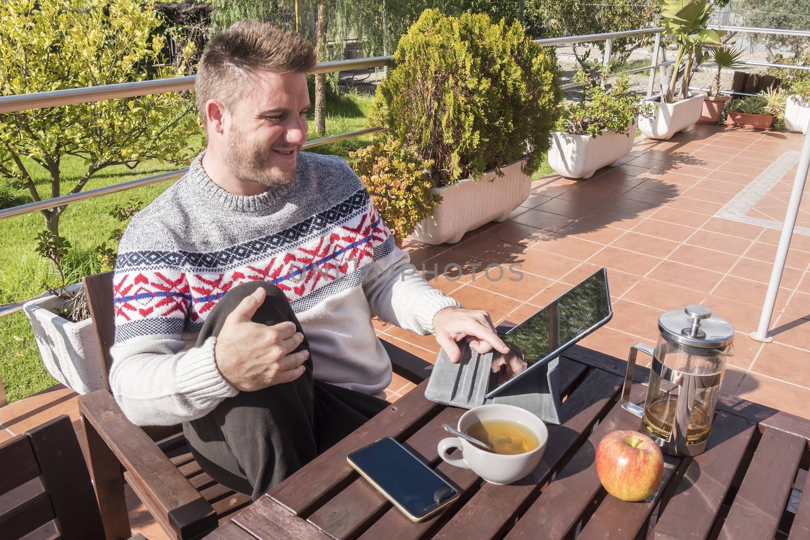 Happy man having breakfast with technology in the garden by max8xam