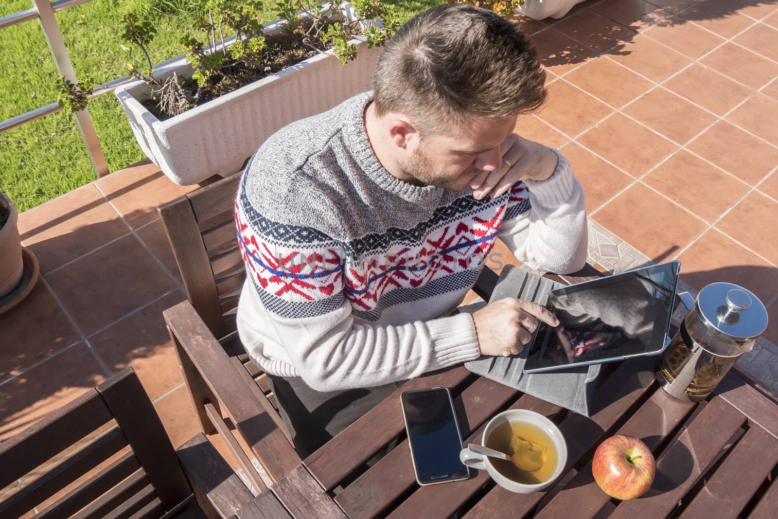 Happy man having breakfast with technology in the garden by max8xam
