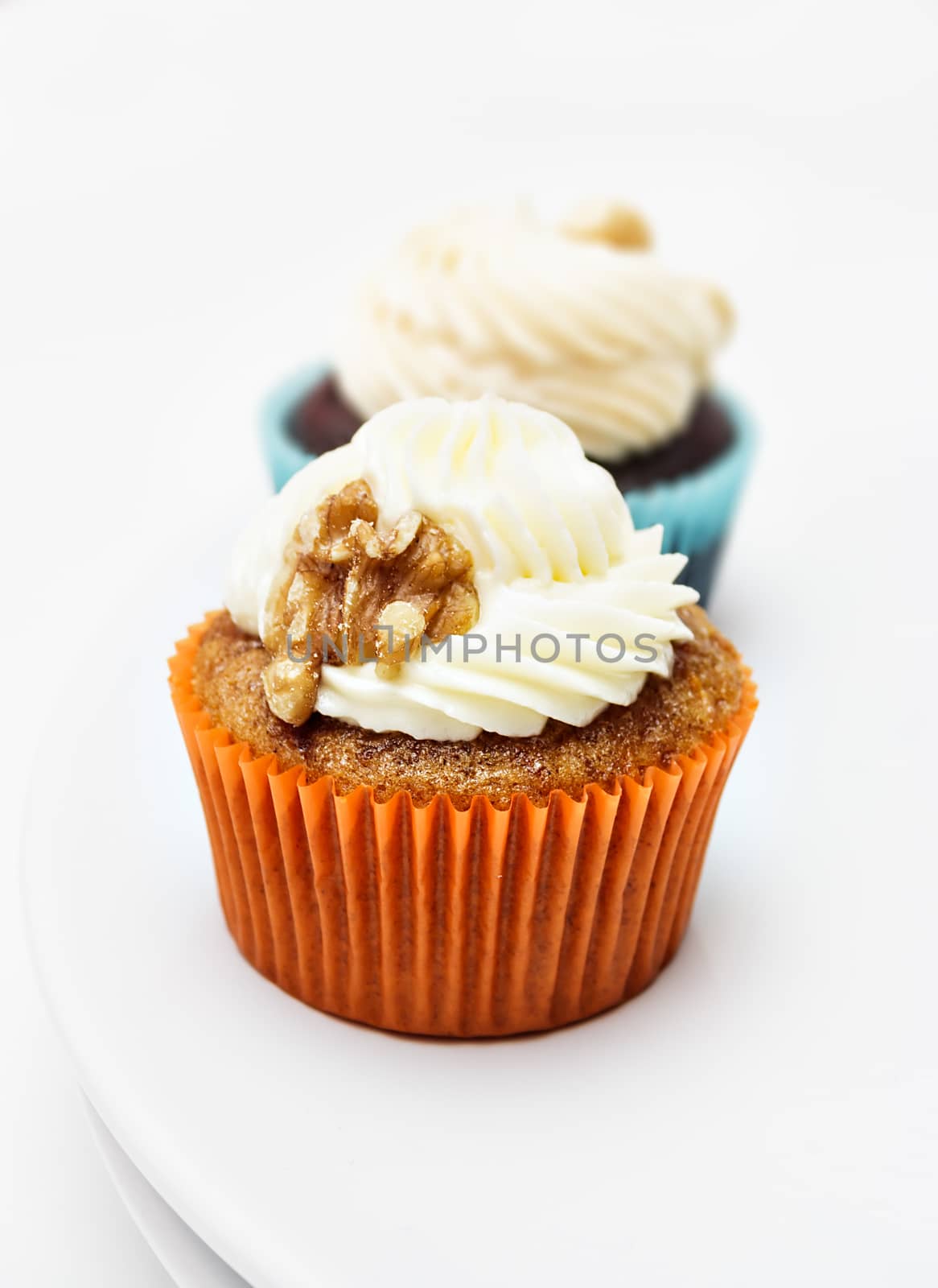 Cupcake with walnuts cream on white background. Vertical image.