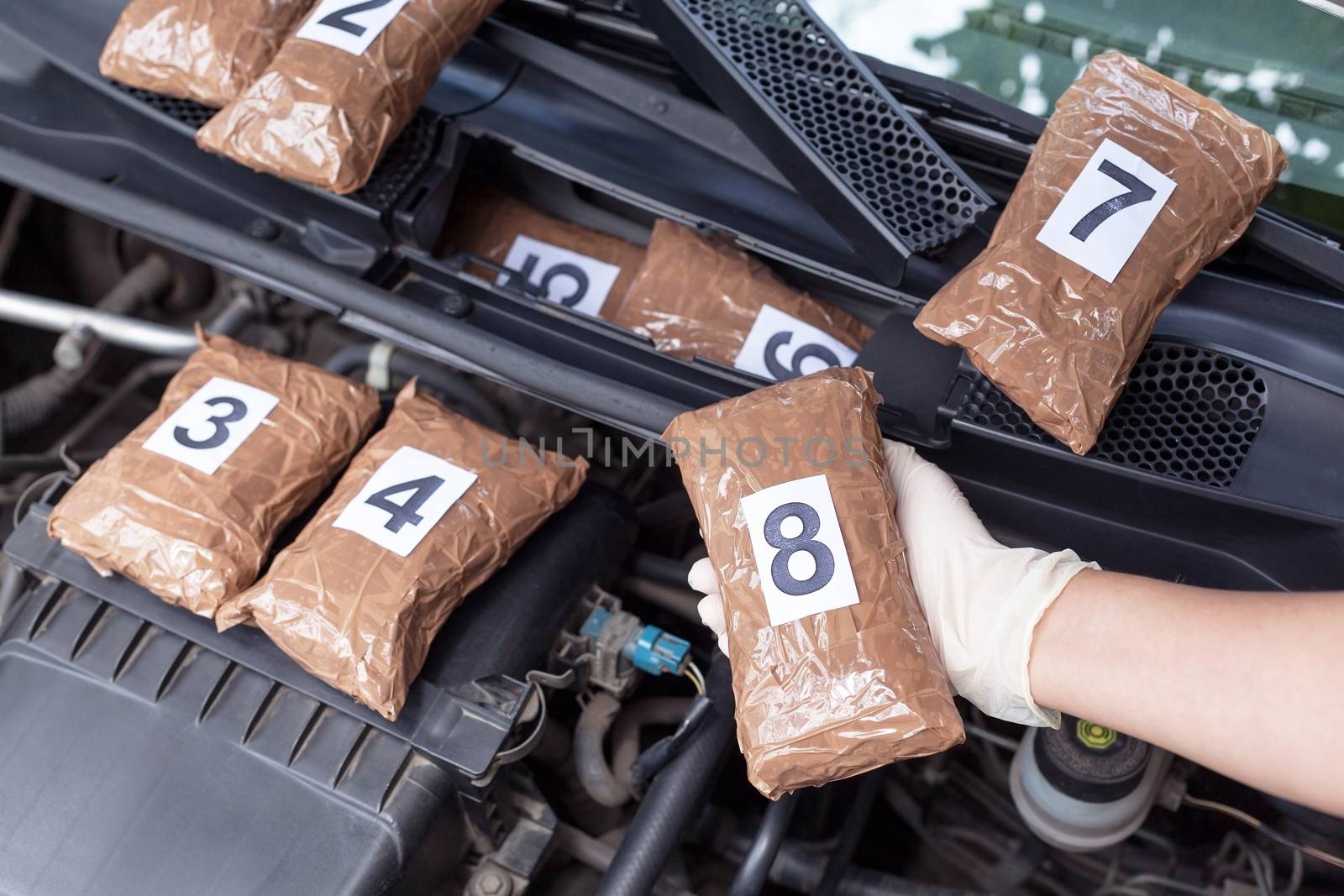 Policeman holding drug package found in engine compartment of a car by wellphoto