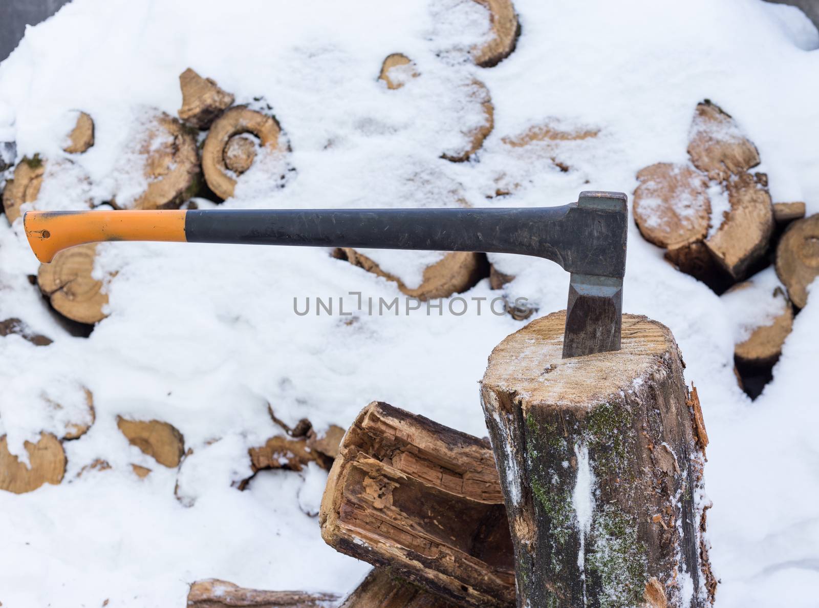 Axe in stump stored firewood in winter by kevol