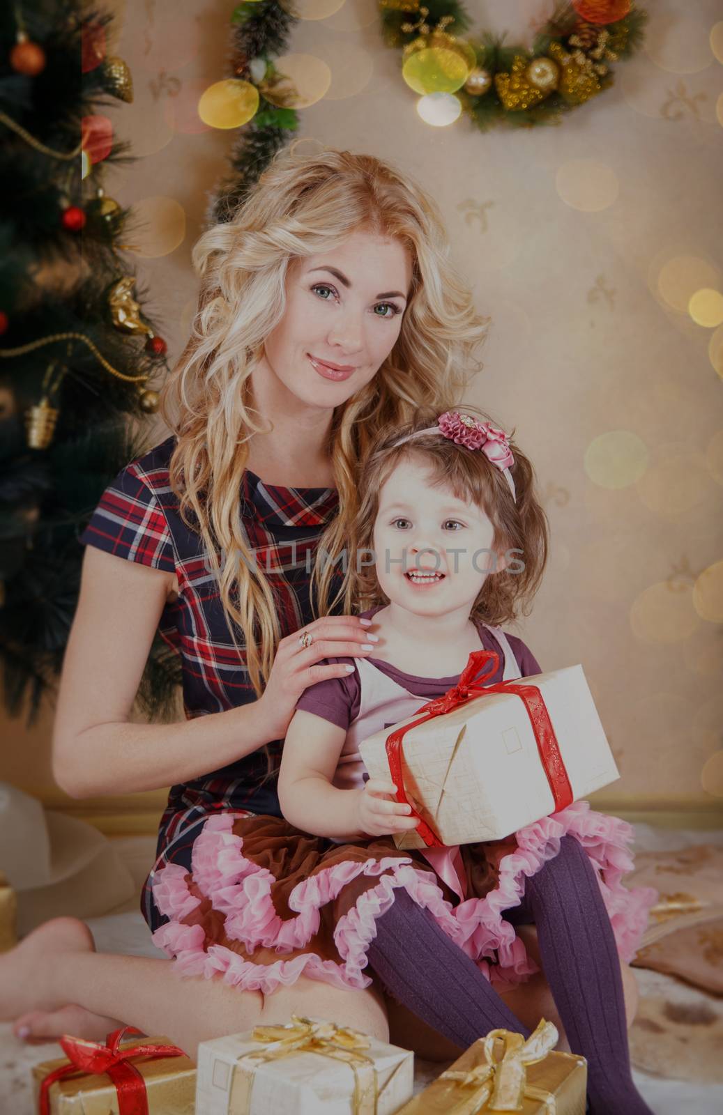 Mother and little daughter with gift-box near Christmas tree