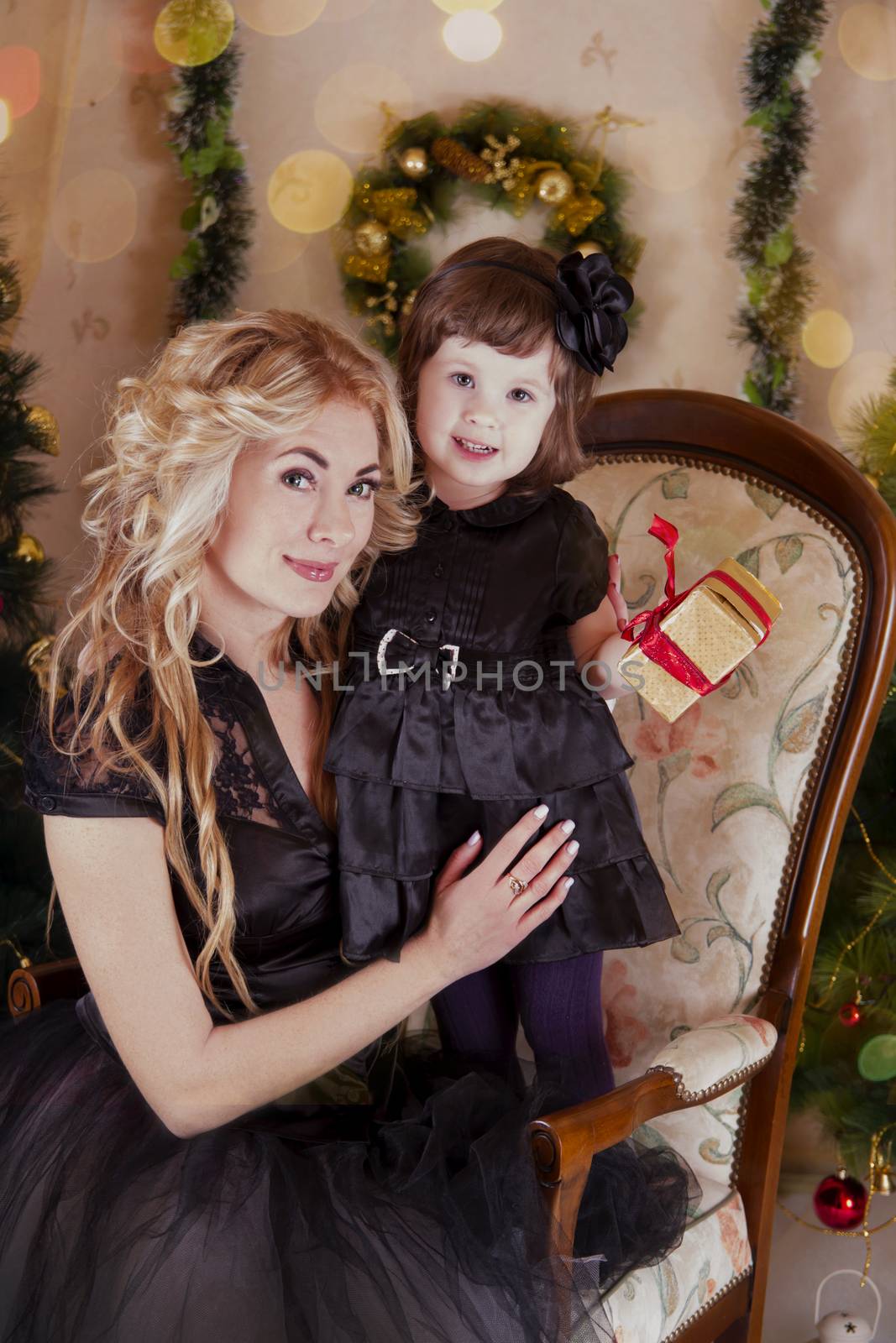 Mother and daughter with gift-box under Christmas tree