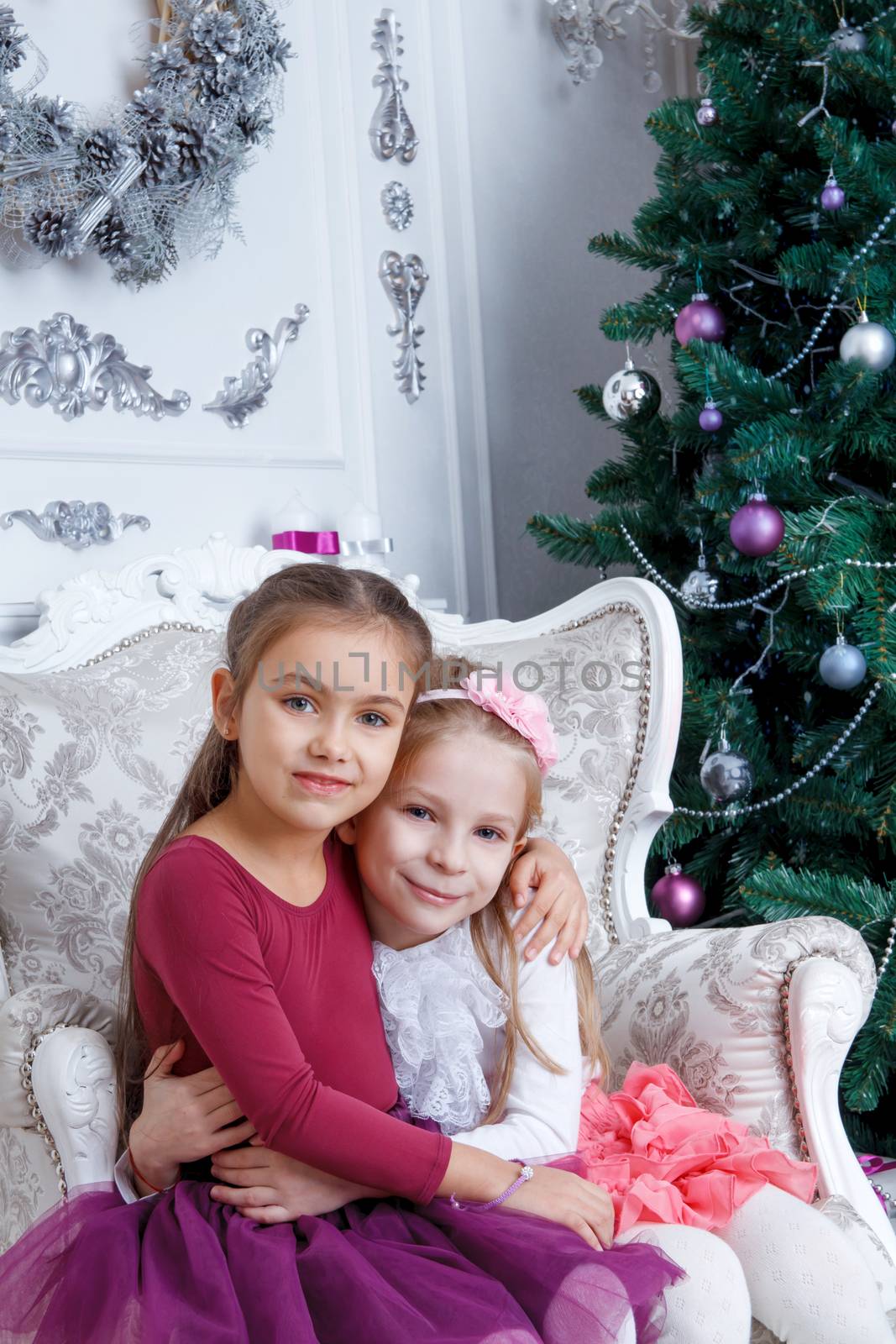 Two girls hugging under Christmas magenta tree
