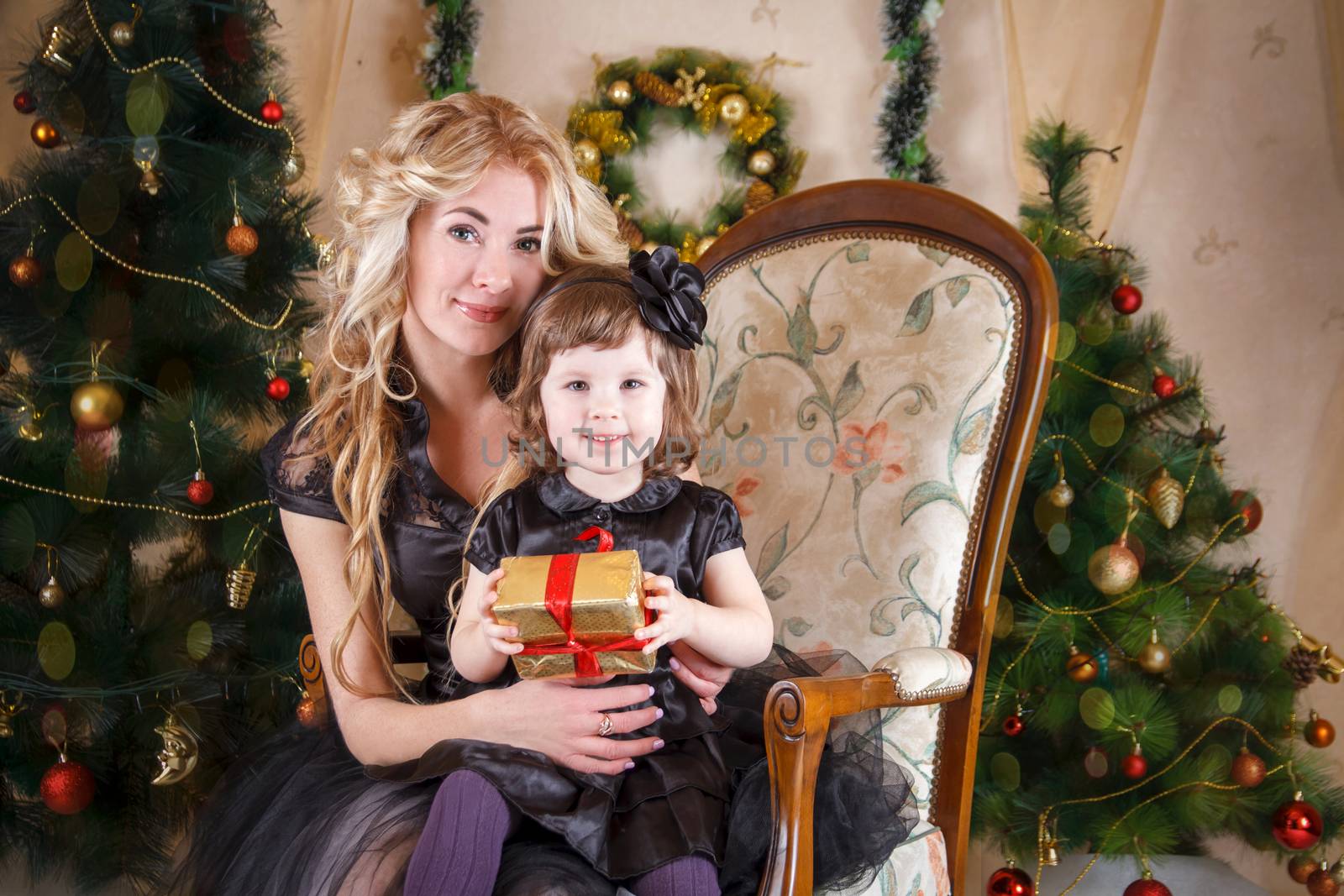 Mother and daughter sitting under Christmas tree with gifts