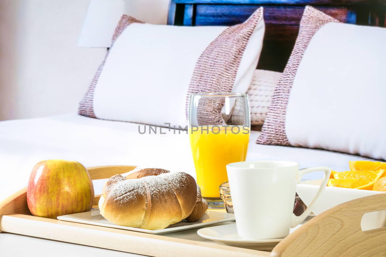 Tray with a continental breakfast on a bed in a hotel room.