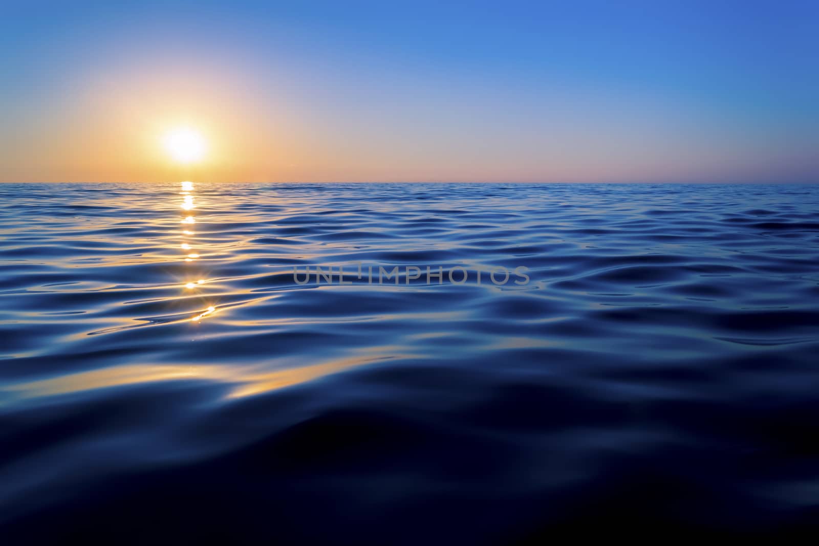 Sunset over the sea. The sun reflected off the waves. Smooth waves. Clear sky