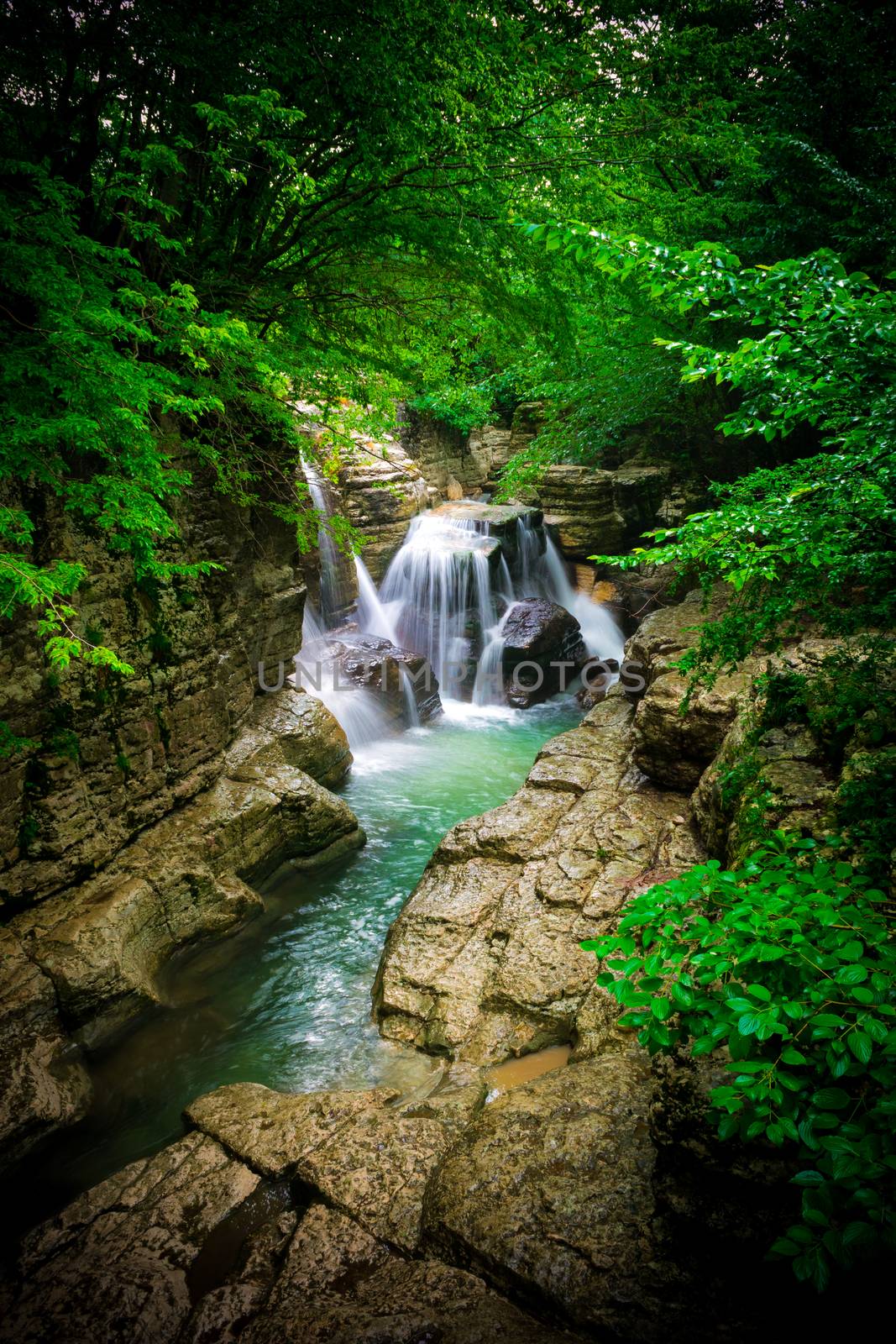 Waterfall in a canyon. Forest around the river. Clear water. Georgia. Vignetting effect.