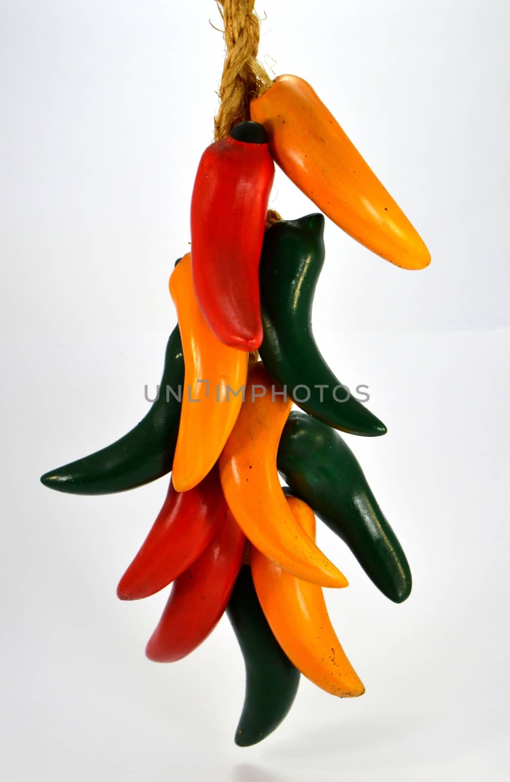 Assortment of red, green and yellow peppers on a rope in white background