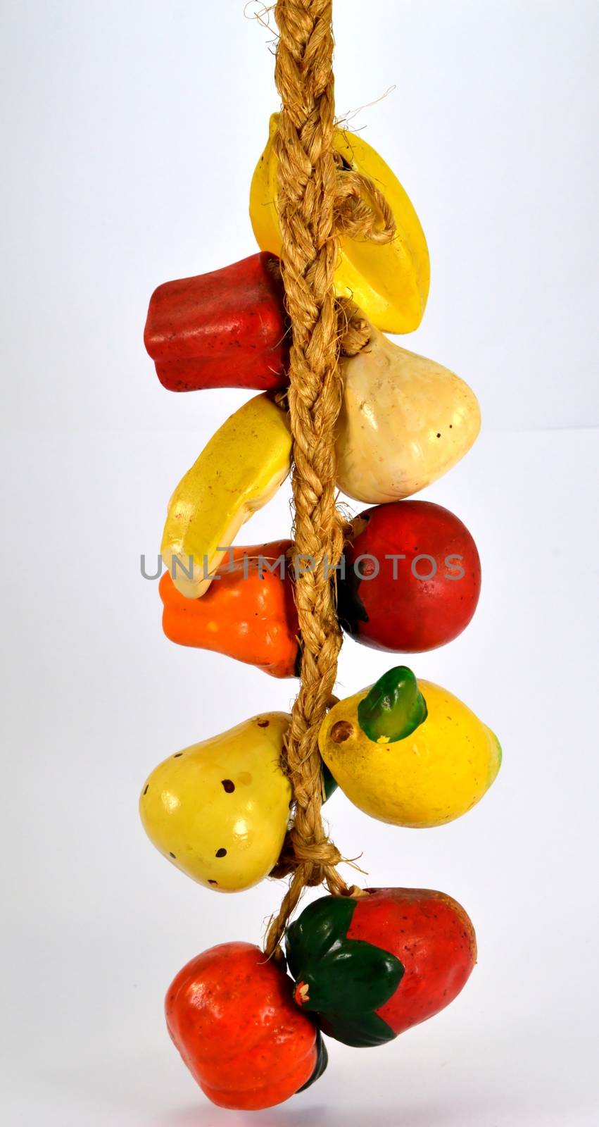 Several fruits and vegetables in bunch on a rope on a white background