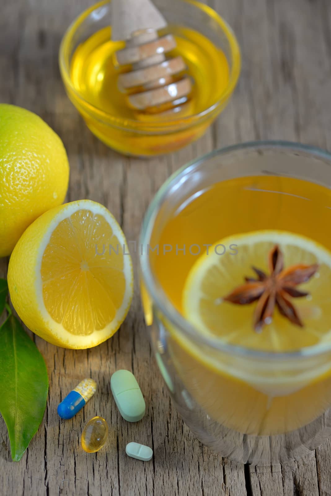 Hot lemon tea and pills on wooden table