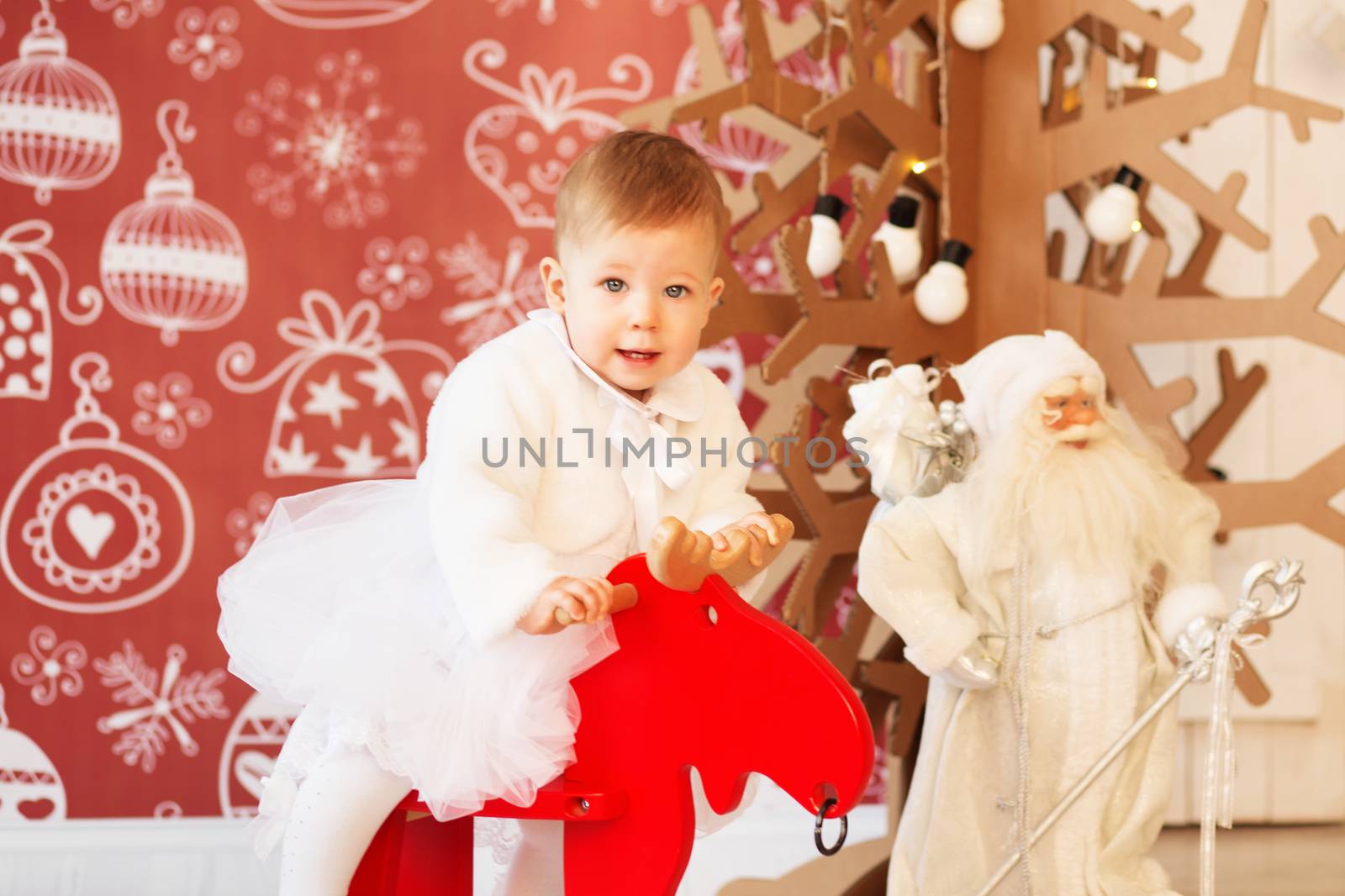 Portrait of a lovely little baby girl riding a rocking deer.