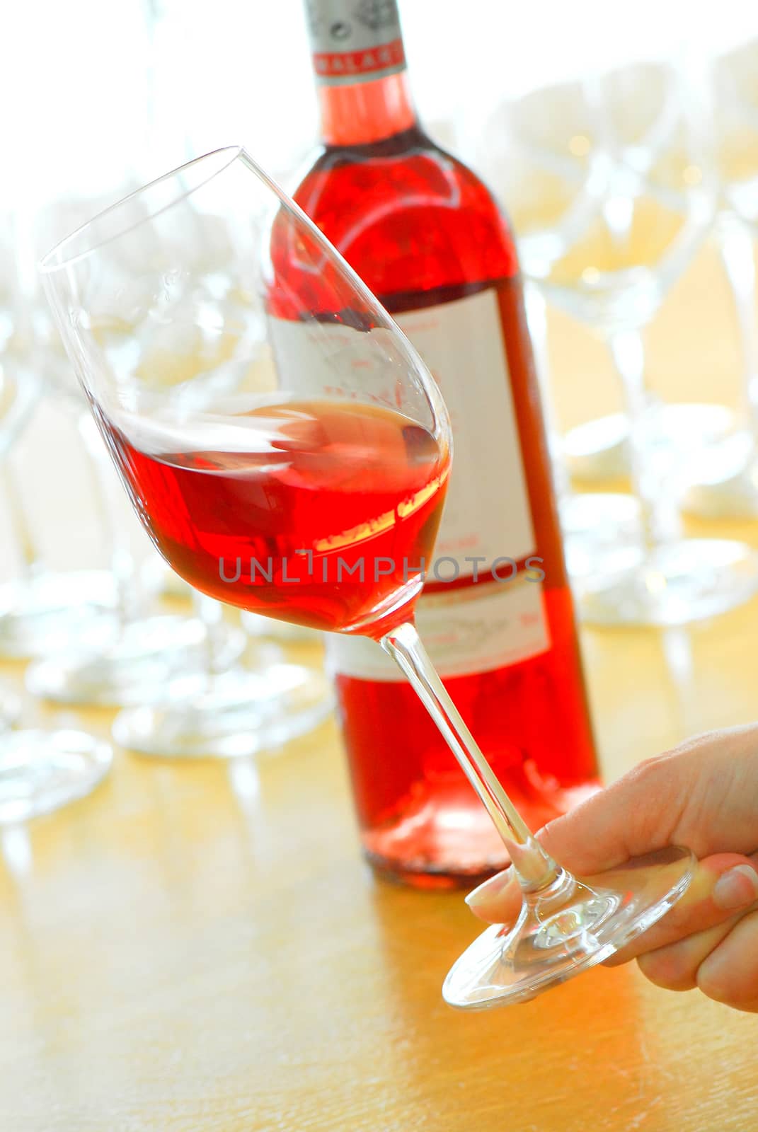 Rose Wine Bottle and a Full Glass in a hand, France