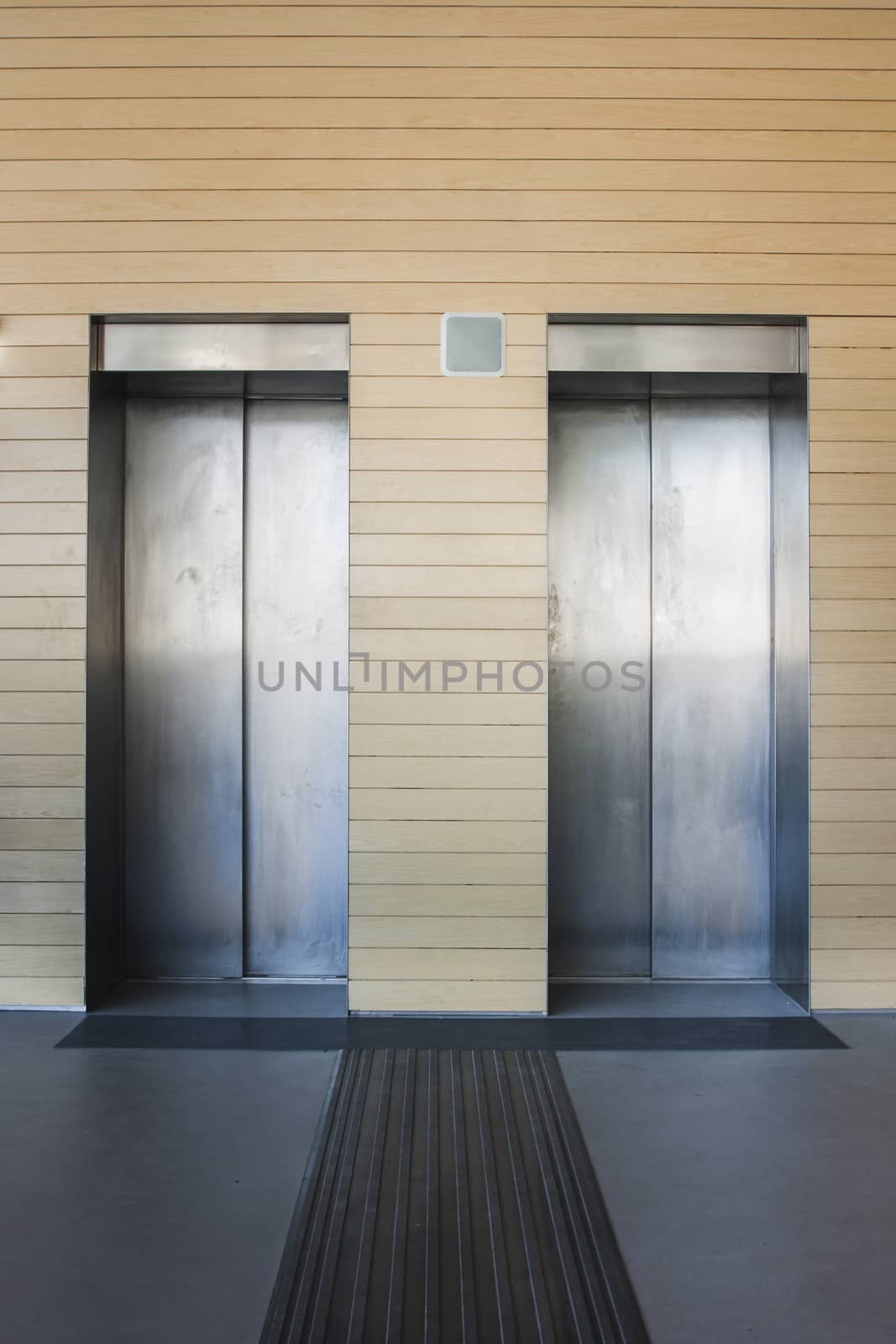Front view of a modern elevator with closed doors in lobby by mailos