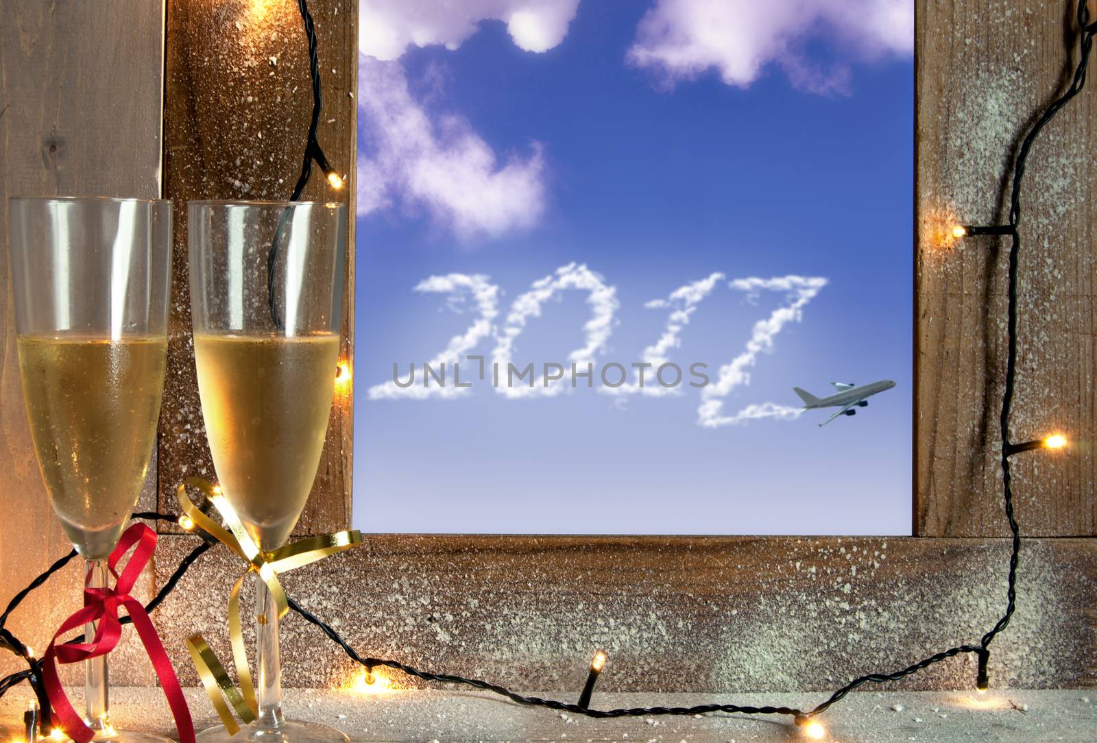 Champagne glasses next to a window with 2017 clouds trail from an airplane 