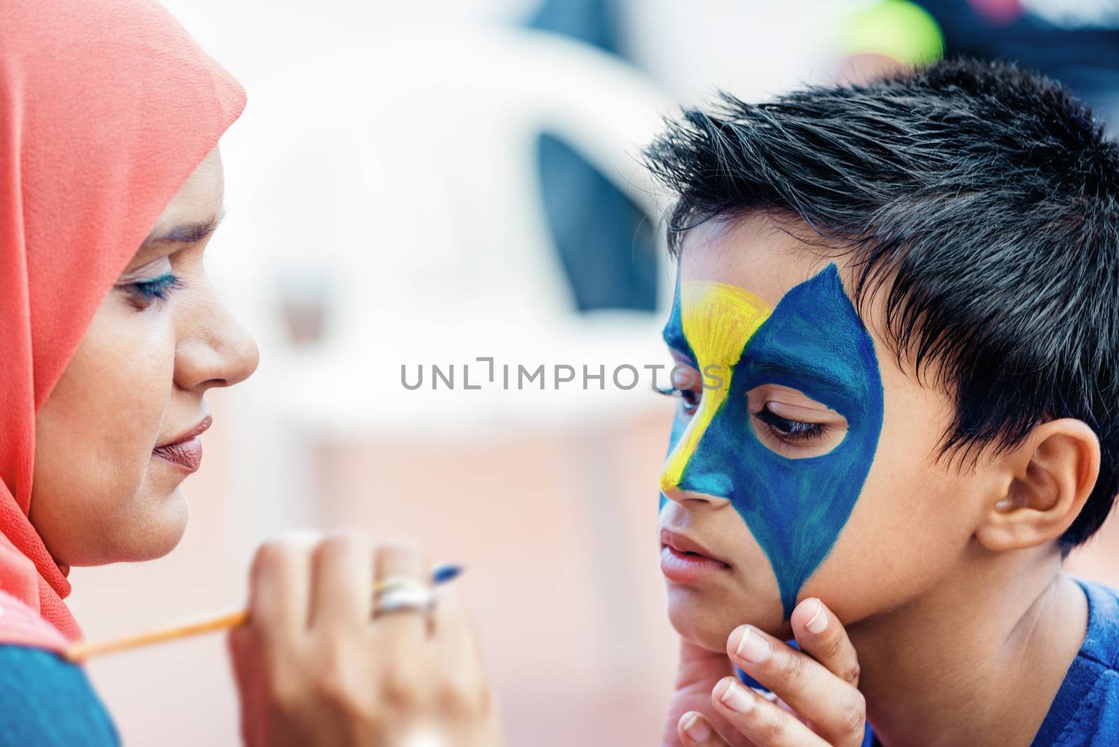 Boy child young having his face painted for fun at a birthday party